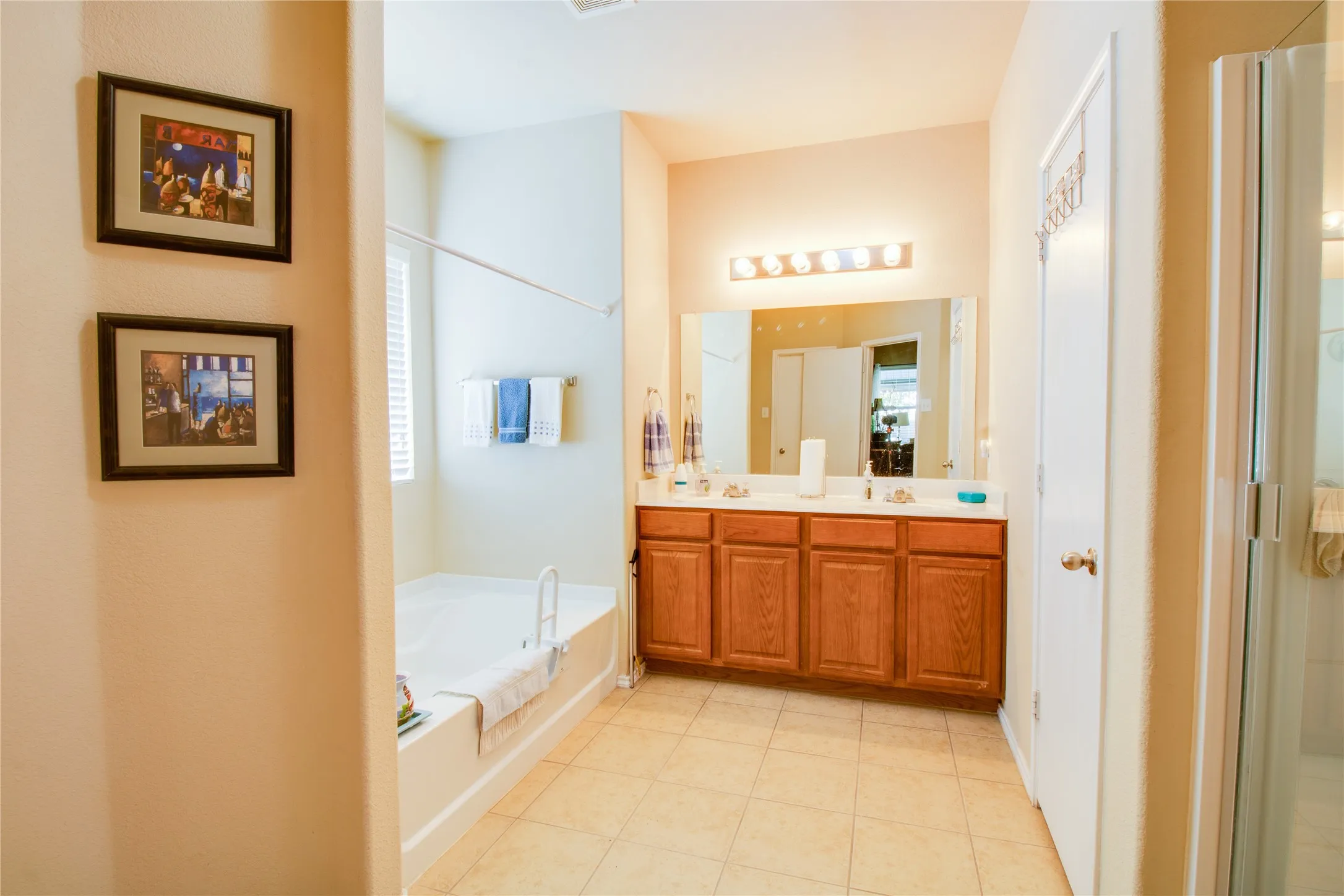 Full bathroom featuring a dual vanity with wood cabinetry, a built-in bathtub, and a separate glass-enclosed shower