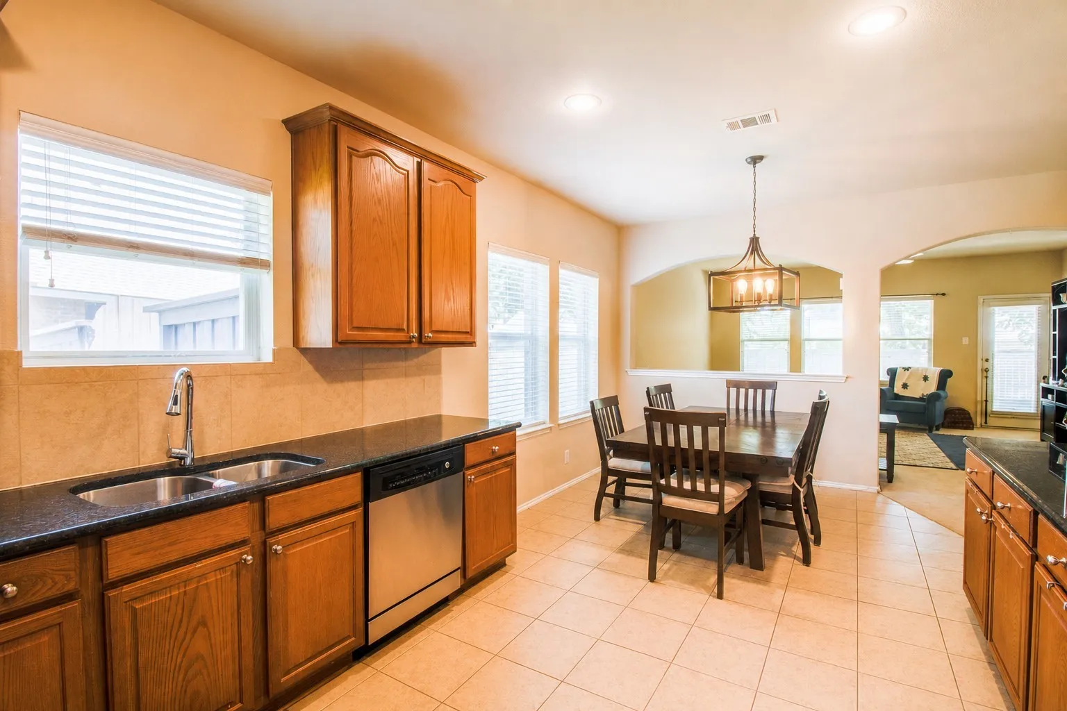Kitchen with wood-finish cabinetry, stainless steel dishwasher, and dual basin sink