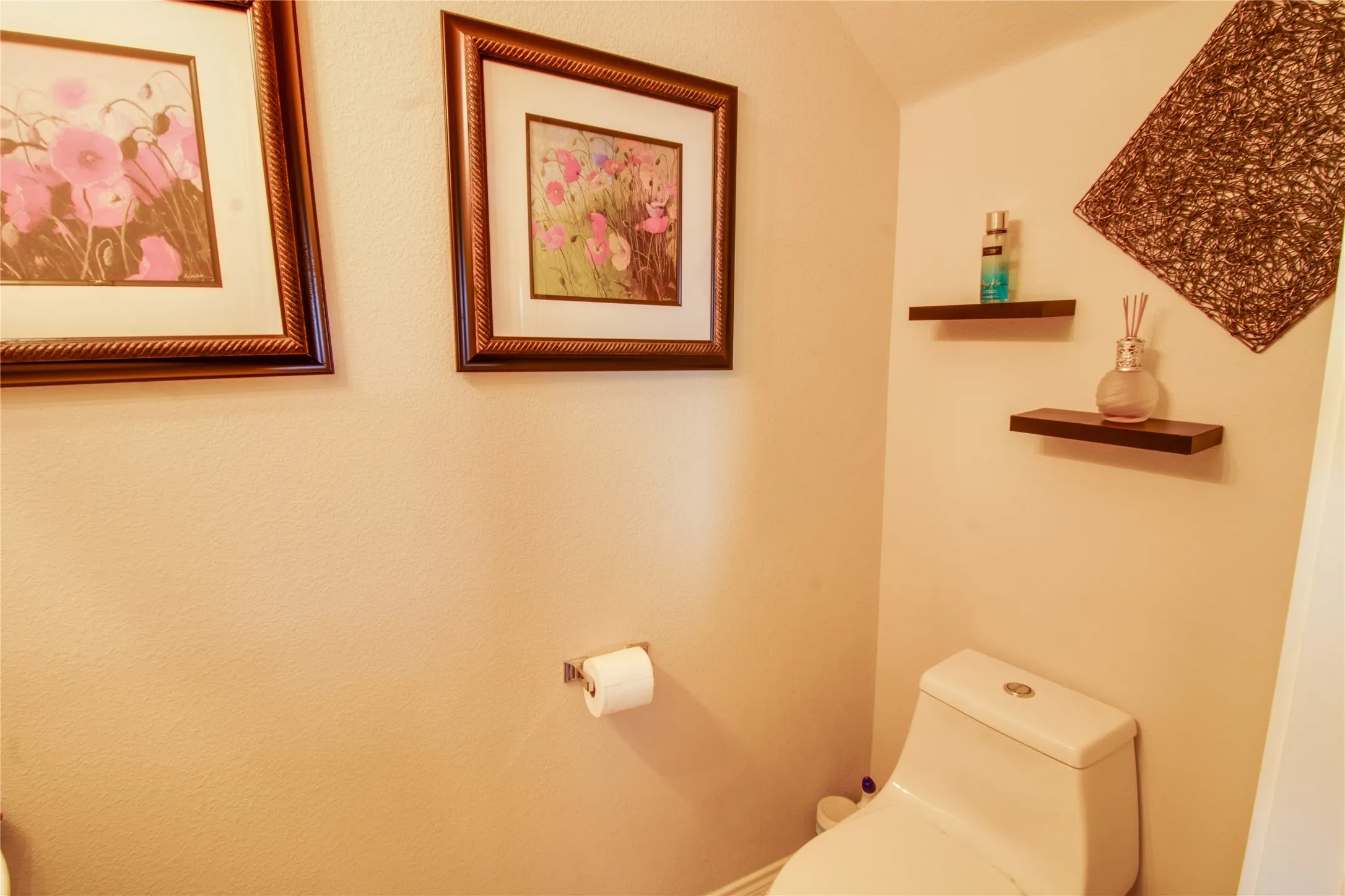 Powder room featuring a two-piece toilet, wall-mounted toilet paper holder, and two floating wood-finish shelves