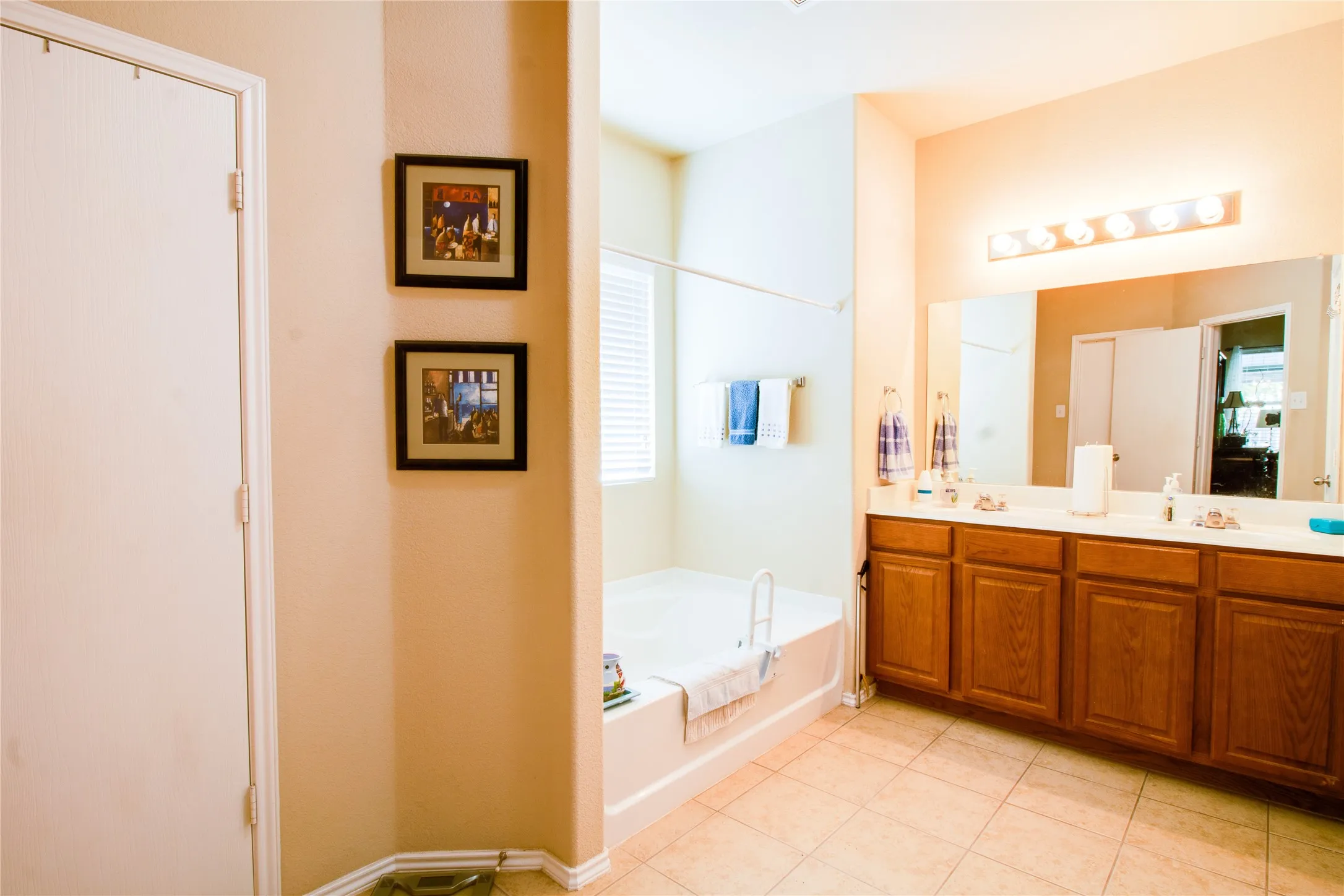 Bathroom featuring a double vanity with wood cabinetry, a large mirror, and a five-light fixture