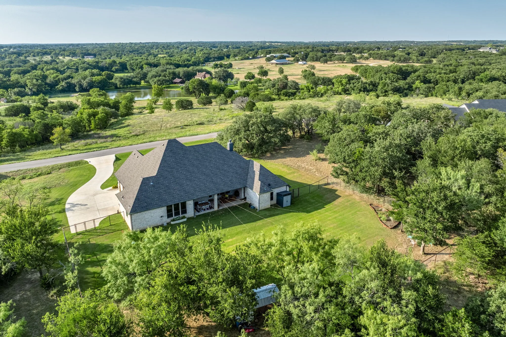 Striking modern residence showcasing a dramatic pitched roof with architectural detailing, positioned on expansive grounds with mature tree landscaping