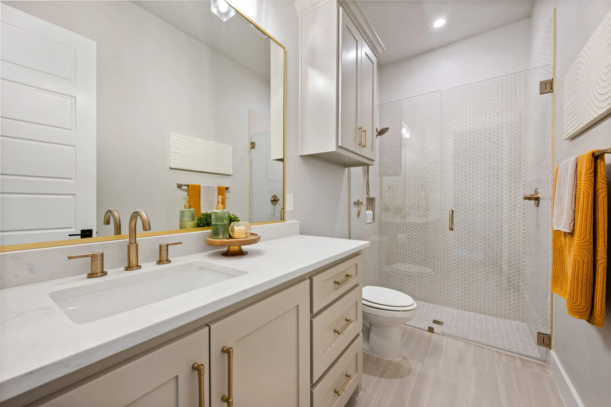 Spa-inspired bathroom featuring vanity with brushed gold hardware, white quartz countertop, and ample storage