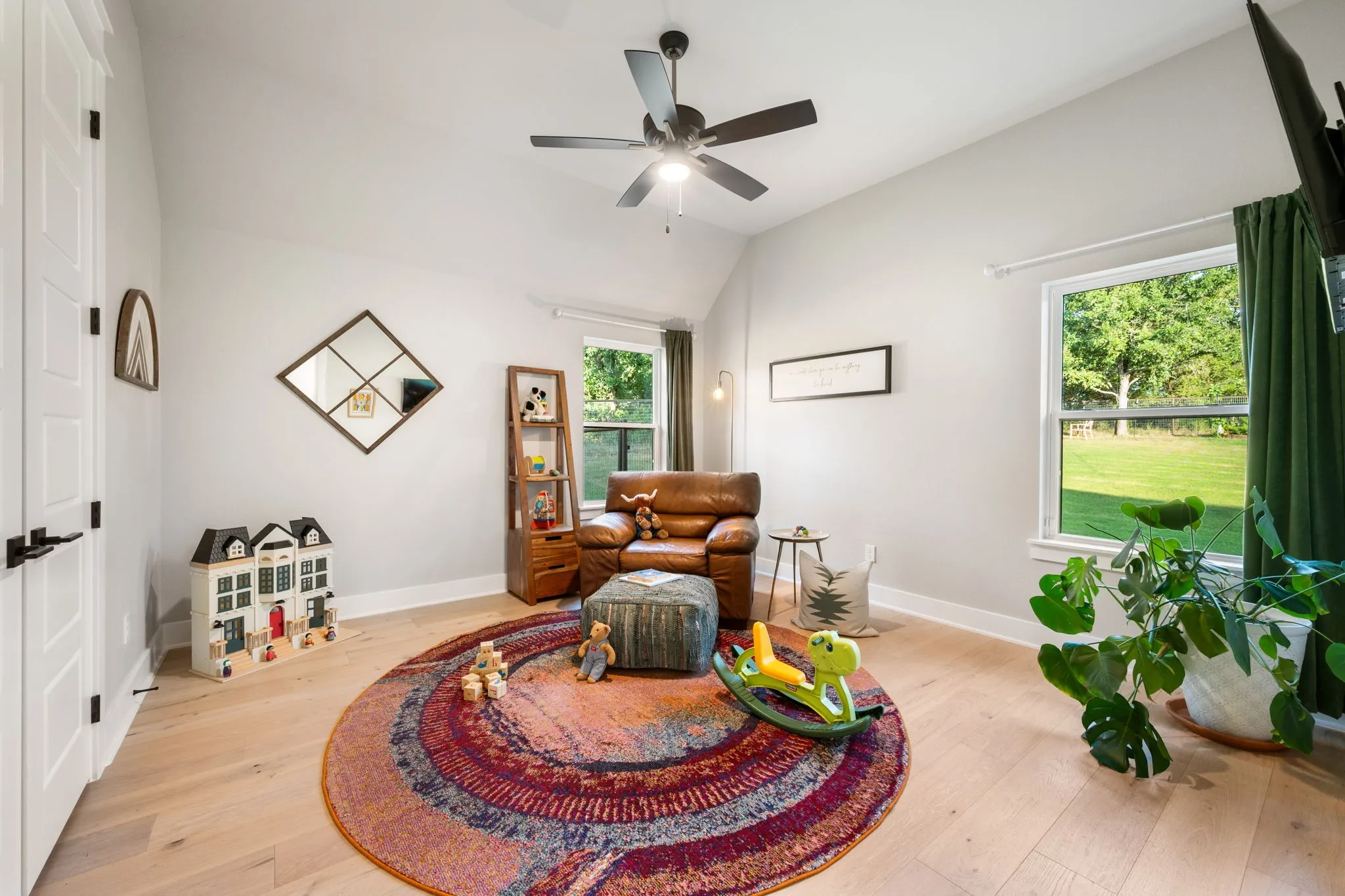 Bright, open living space featuring ceiling fan with integrated lighting, walk in closet and expansive windows framed