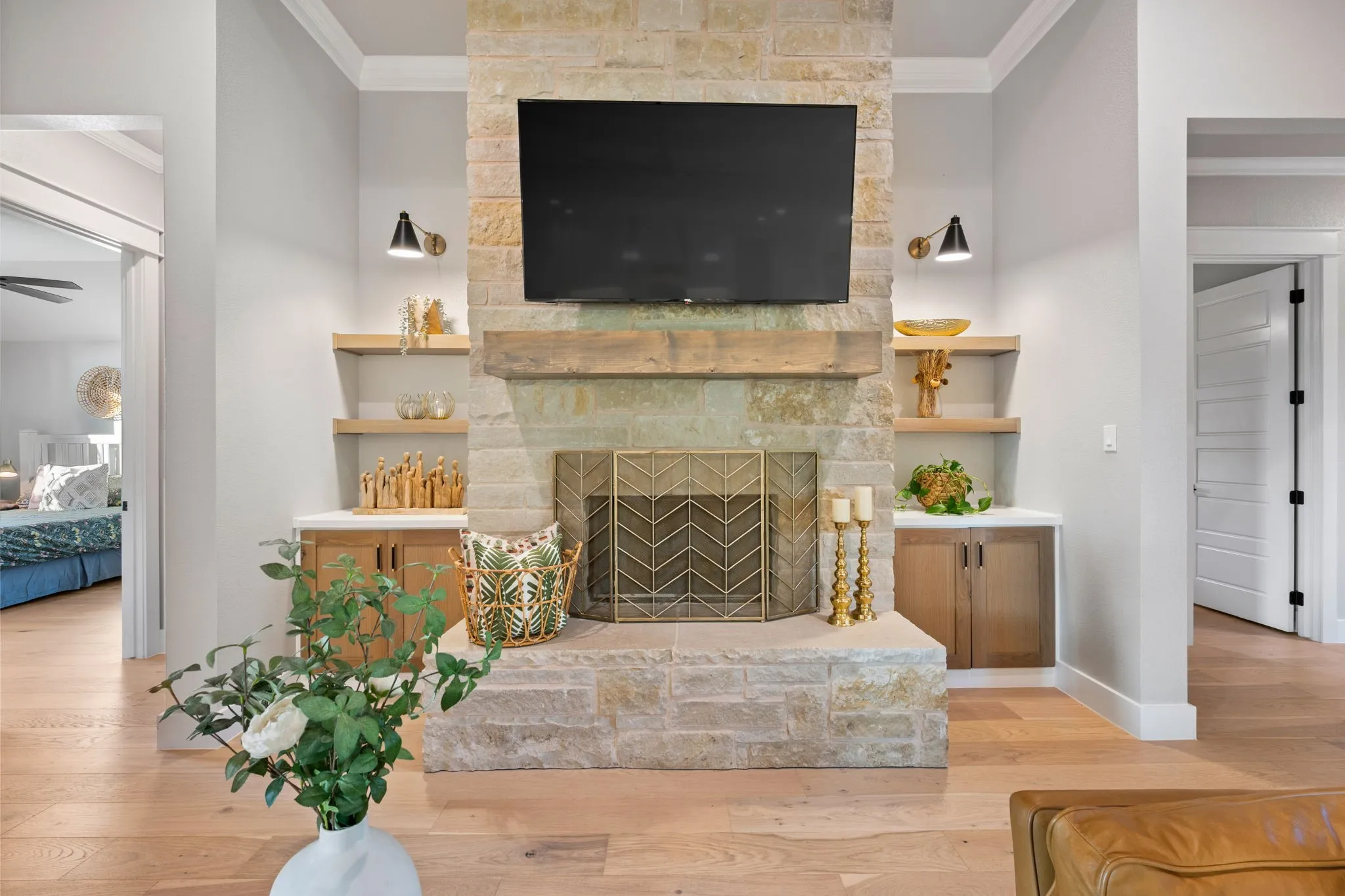 Stone fireplace with a substantial wood mantel, flanked by built-in cabinetry and floating wood shelves
