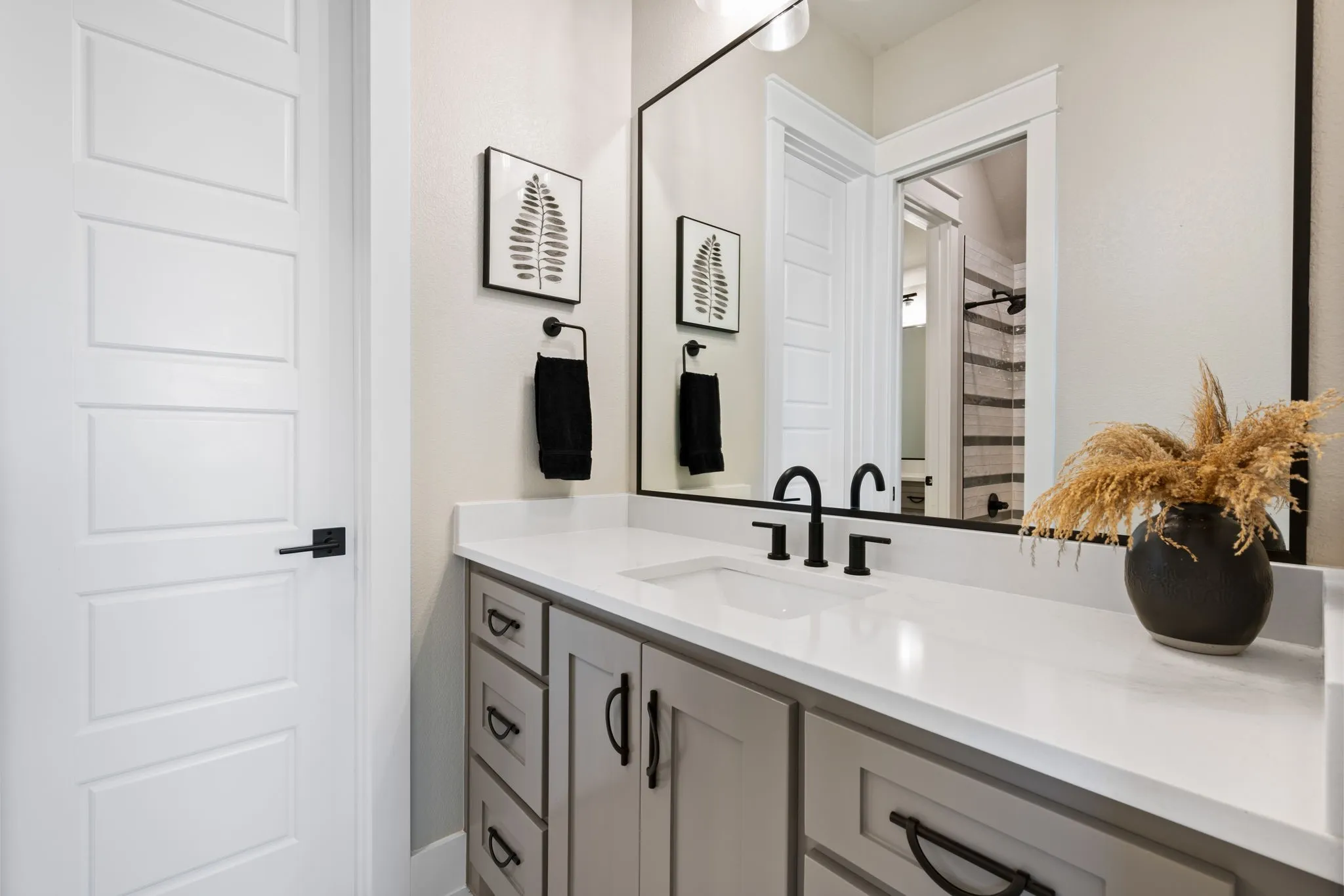 Vanity featuring an integrated sink with matte black fixtures and a large wall-mounted mirror