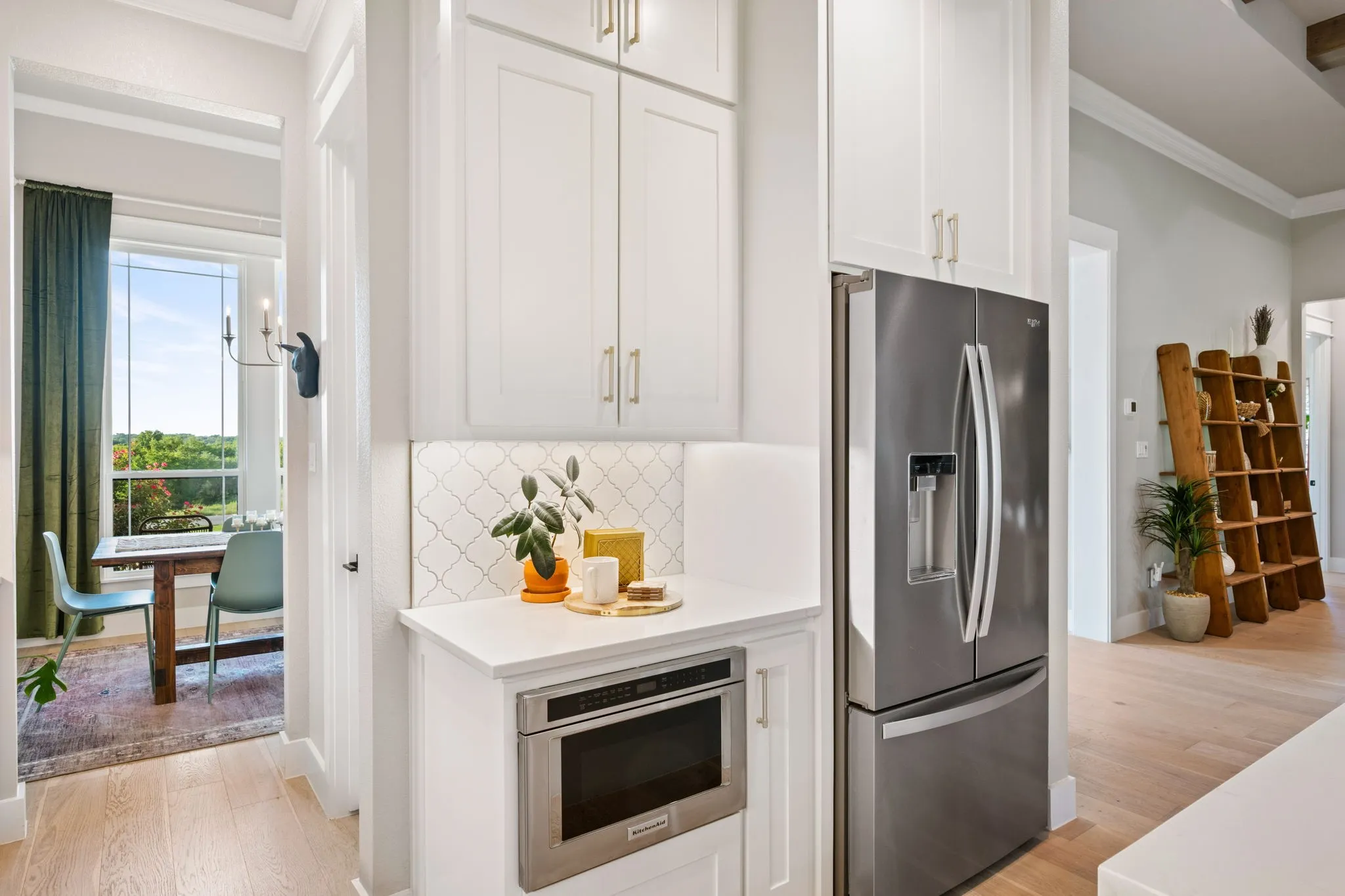Modern kitchen featuring white shaker-style cabinetry, white subway tile backsplash, and stainless steel appliances, built-in microwave, and smooth-top range
