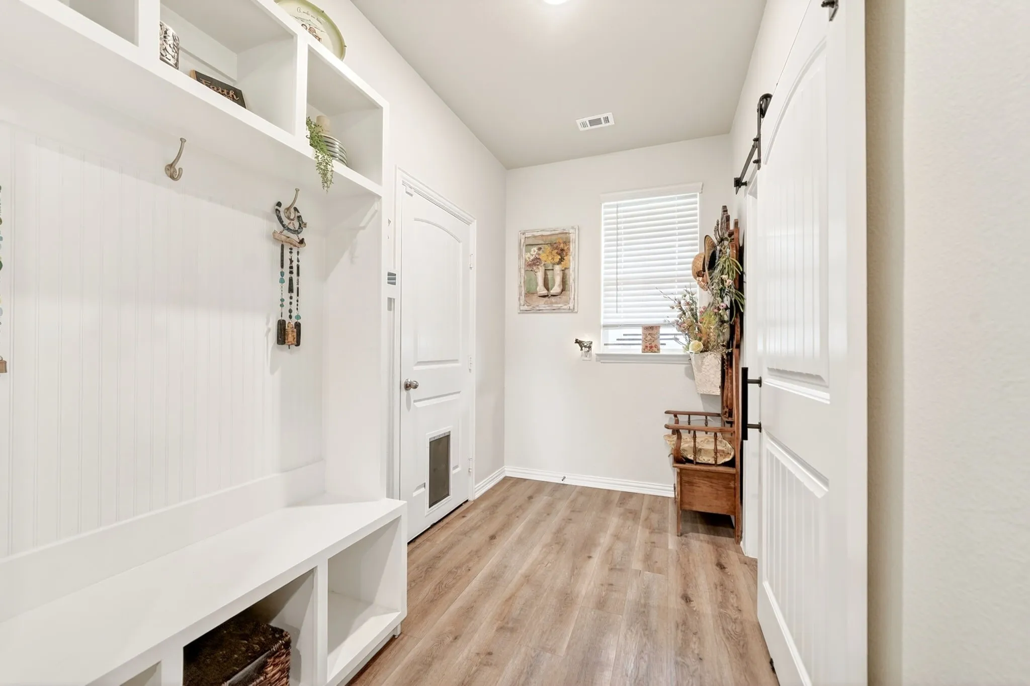 Entryway featuring a built-in white mudroom bench with cubby storage, beadboard backing, and upper shelving