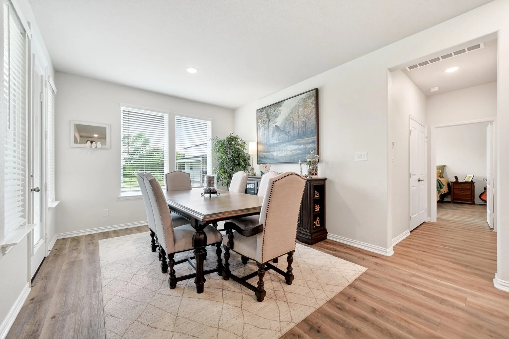 Spacious dining area featuring wood-finish flooring, recessed lighting, and multiple windows with blinds