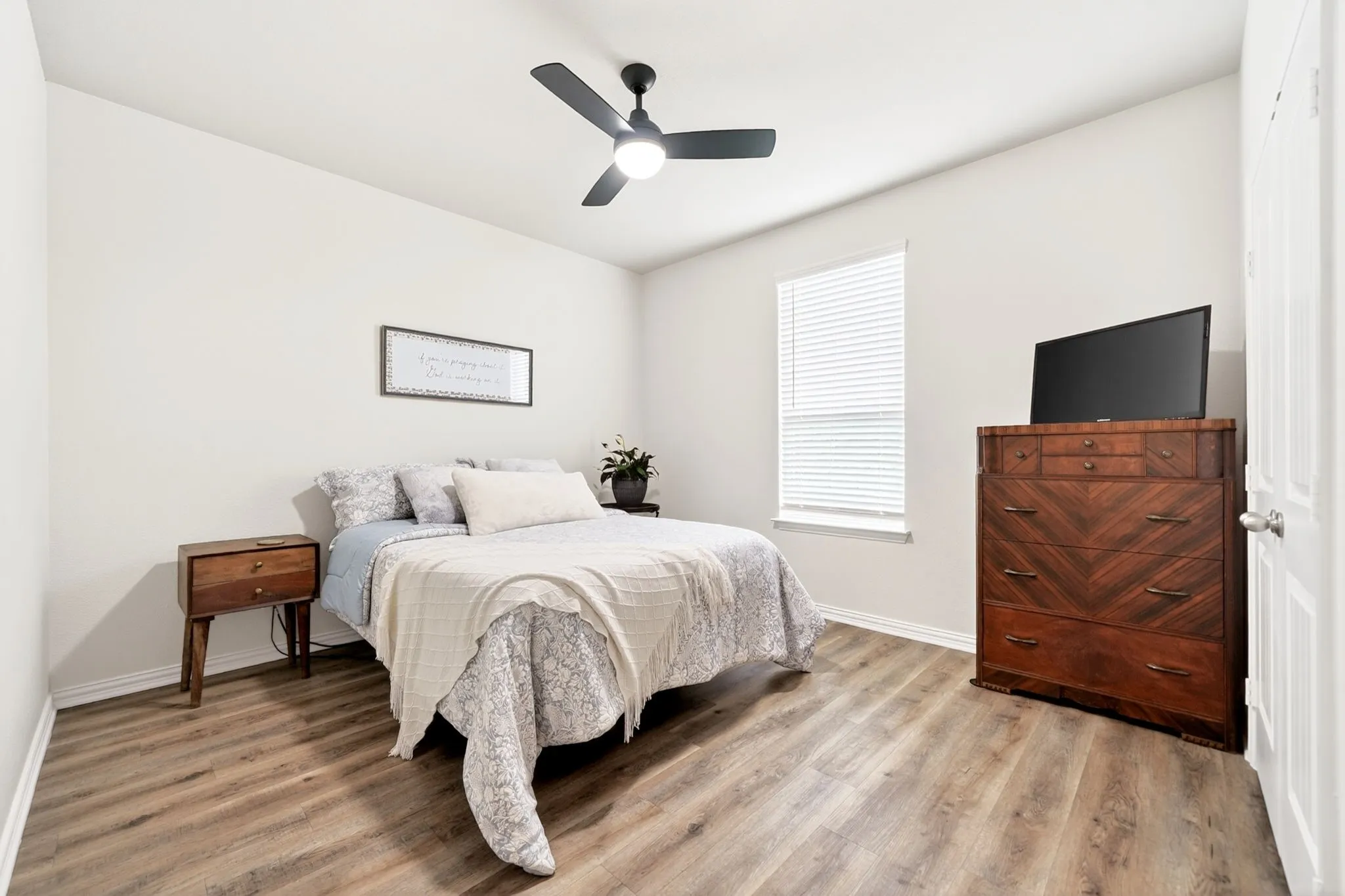 Room featuring wood-finish flooring, a single window with blinds, and white painted walls
