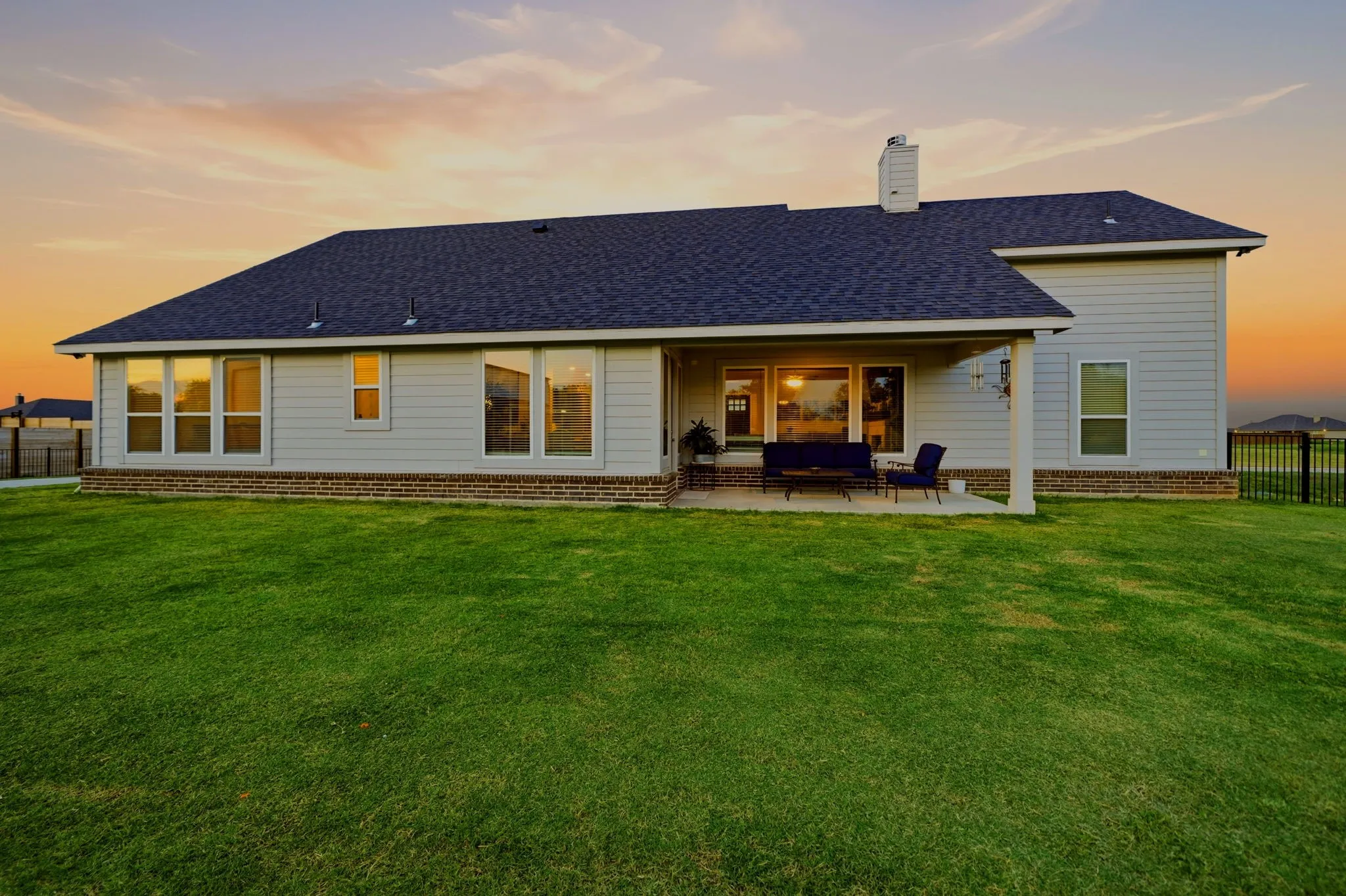 Expansive green lawn with a modern light-toned siding exterior