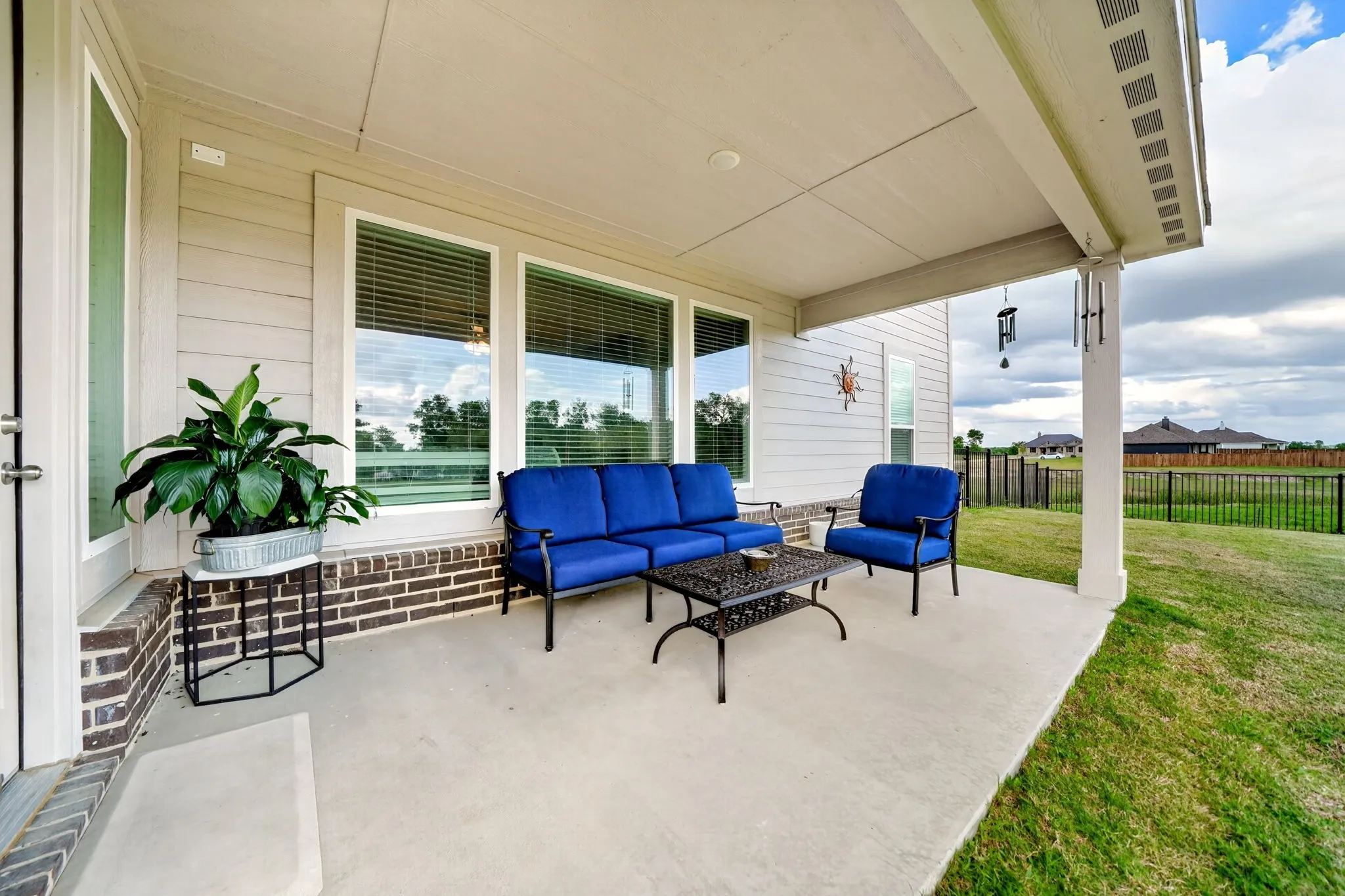 Covered concrete patio with a painted ceiling, featuring siding and brick exterior accents