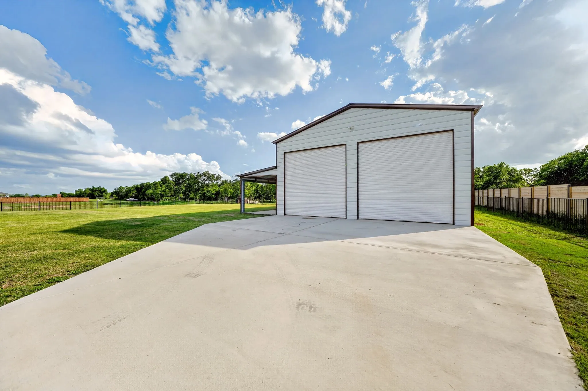Detached two-bay garage structure featuring metal siding, twin overhead doors, and an attached covered carport