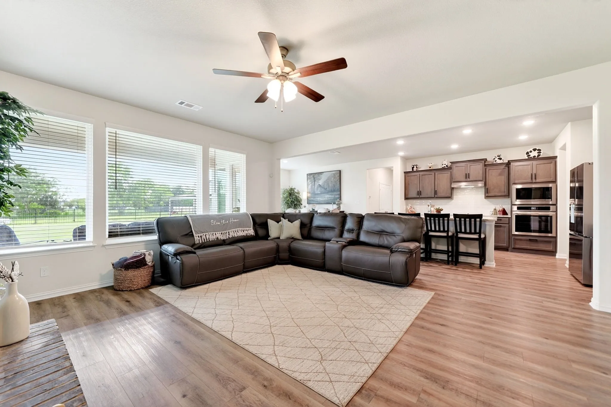 Expansive living area with wood-finish flooring, recessed lighting, and a ceiling fan