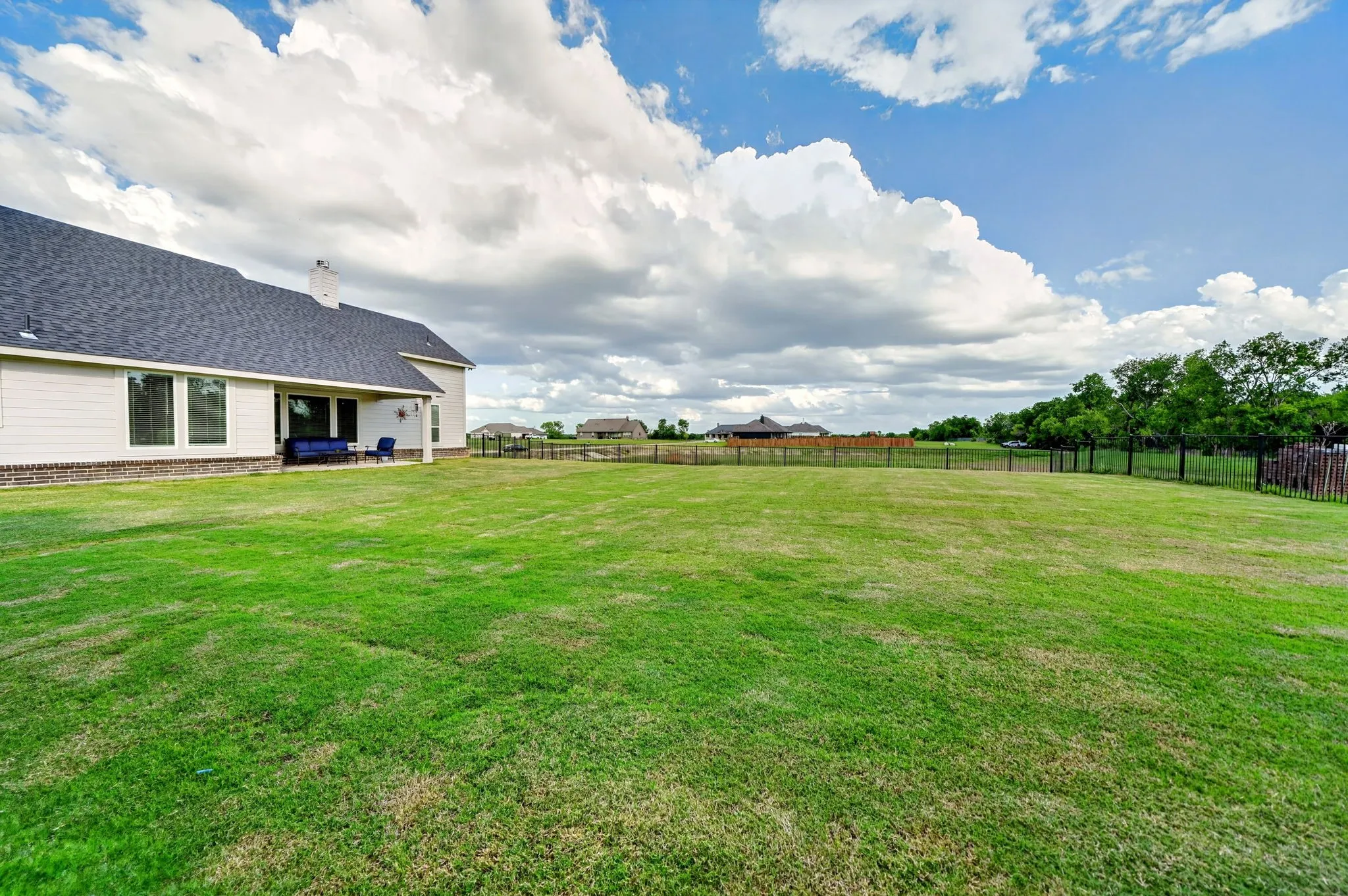 Expansive green lawn with a large rear patio and a privacy fence
