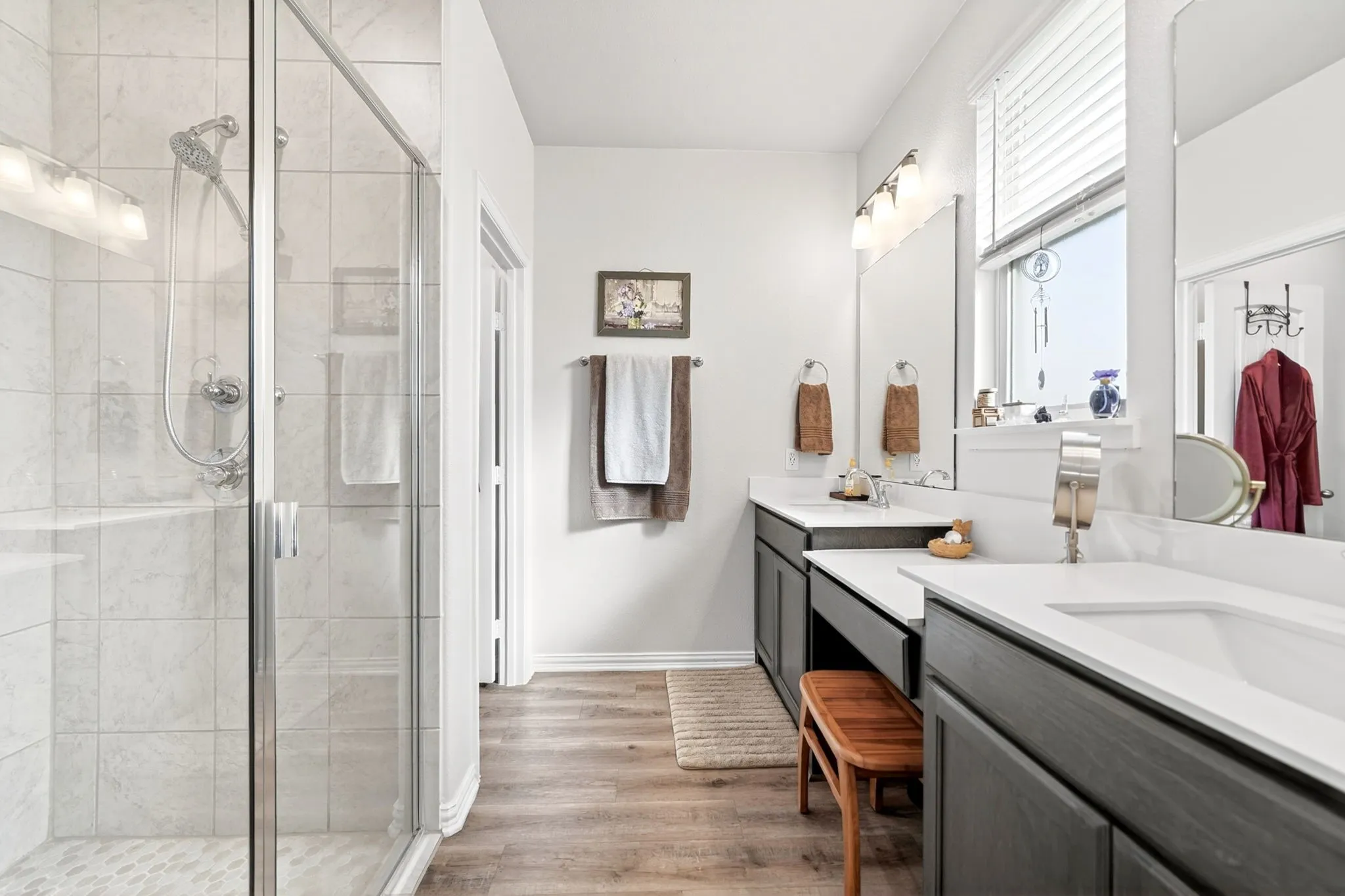 Spacious bathroom featuring a glass-enclosed shower with tiled walls and a built-in shower bench