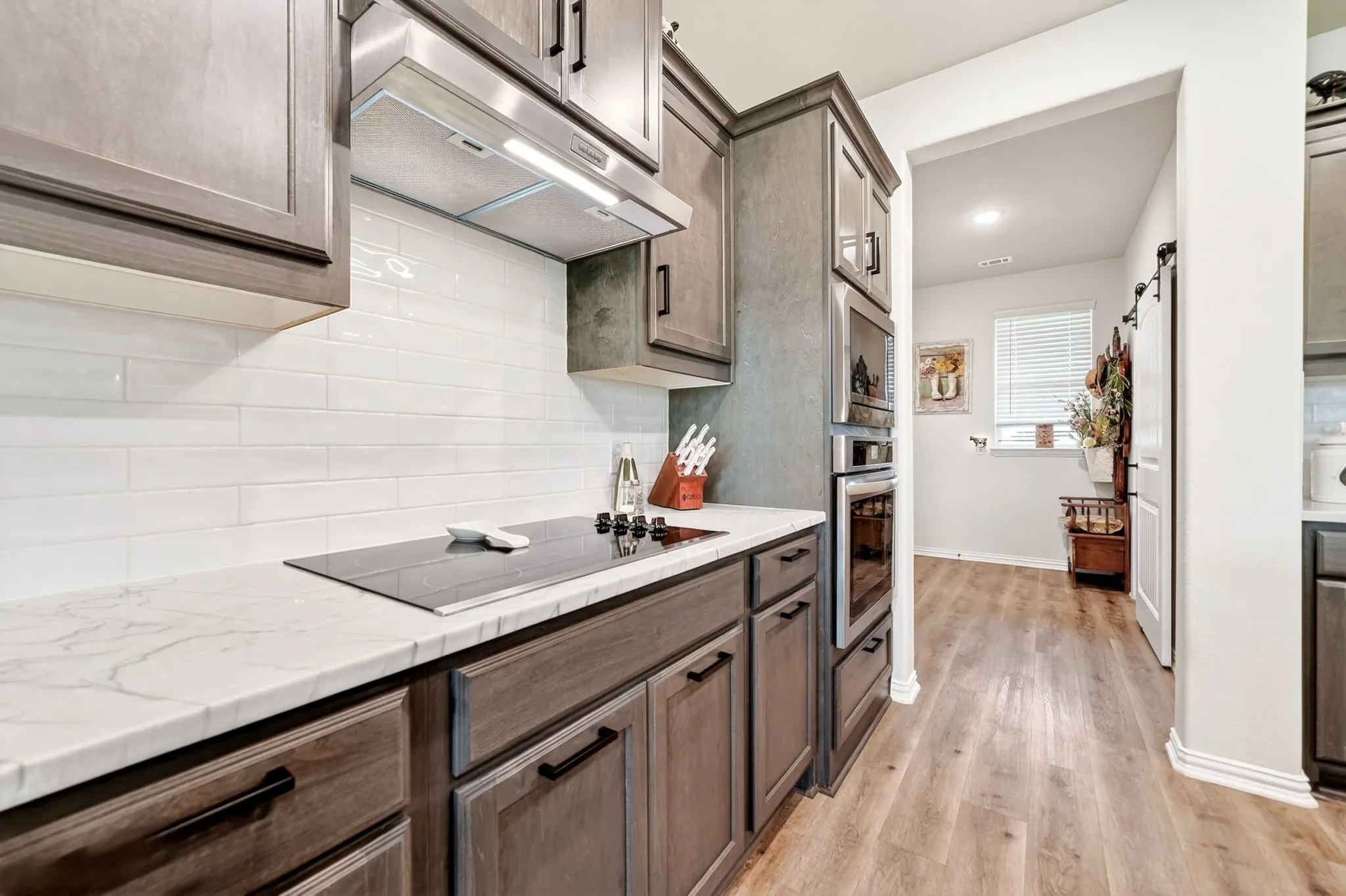 Kitchen featuring dark wood-finish cabinetry, white subway tile backsplash, a built-in oven, and a built-in microwave