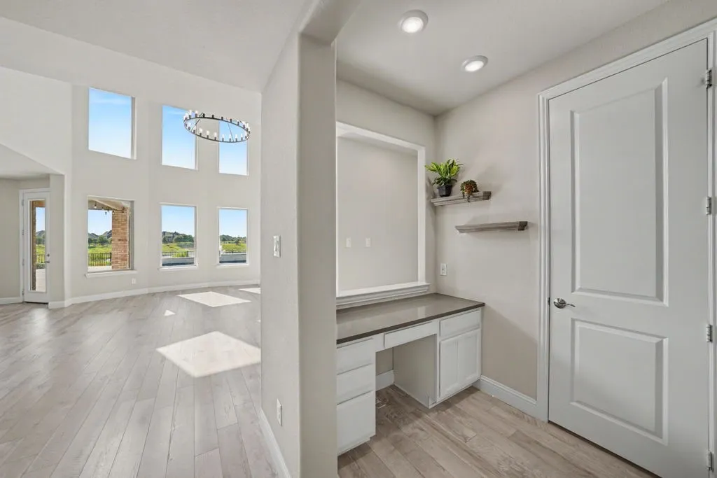 Two-story ceiling, multiple windows, wood-finish flooring, built-in desk with countertop, recessed lighting