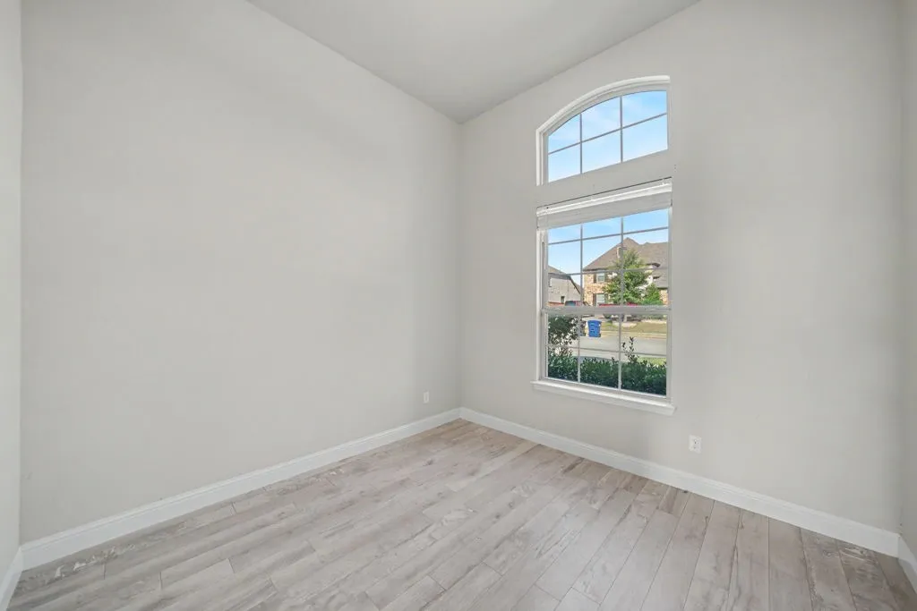Arched transom window above a large picture window, featuring wood-finish flooring and neutral wall tones