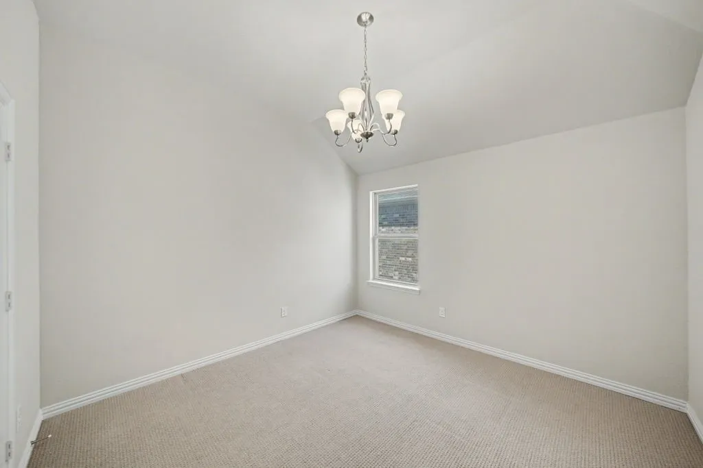 Vaulted ceiling with a chandelier, neutral wall paint, window with white trim, and carpeted flooring