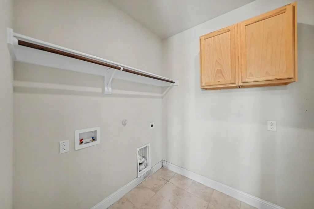 Neutral wall color, wood-finish cabinetry, built-in shelving with hanging rod, and tiled flooring