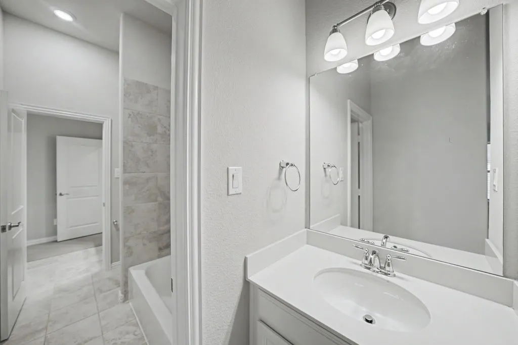 Bathroom featuring a vanity with an integrated sink, polished chrome faucet, and a large mirror with overhead lighting