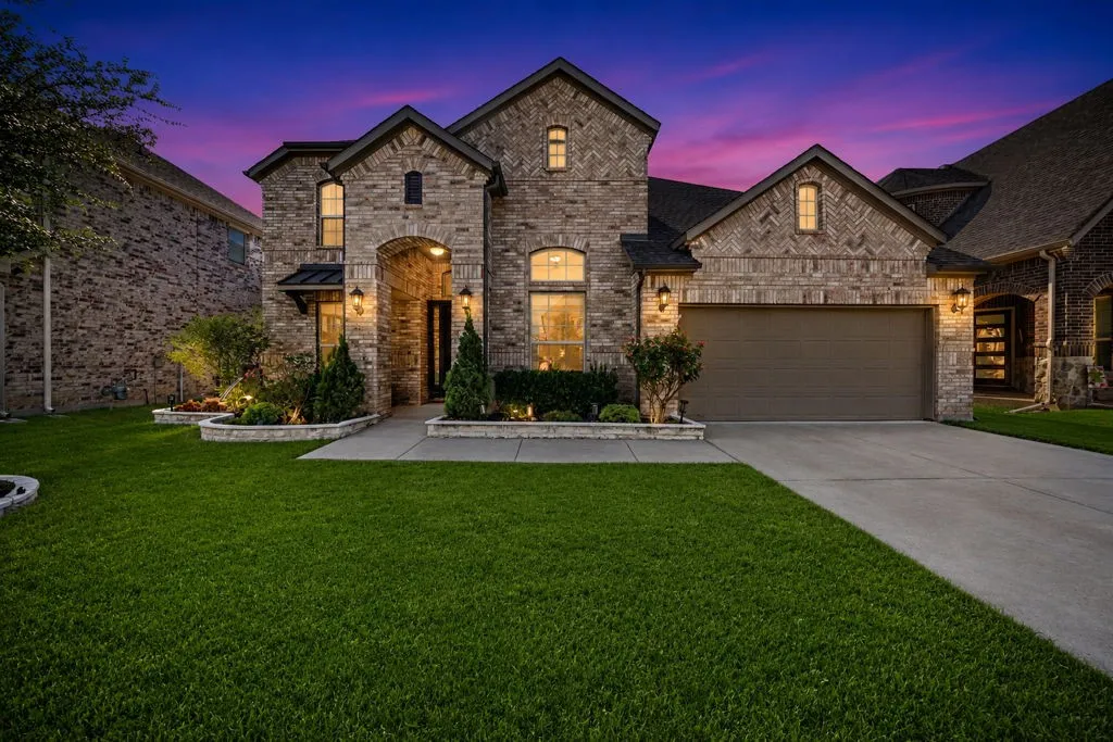Brick and stone exterior with architectural gables, arched entry, a two-car garage, and mature landscaping