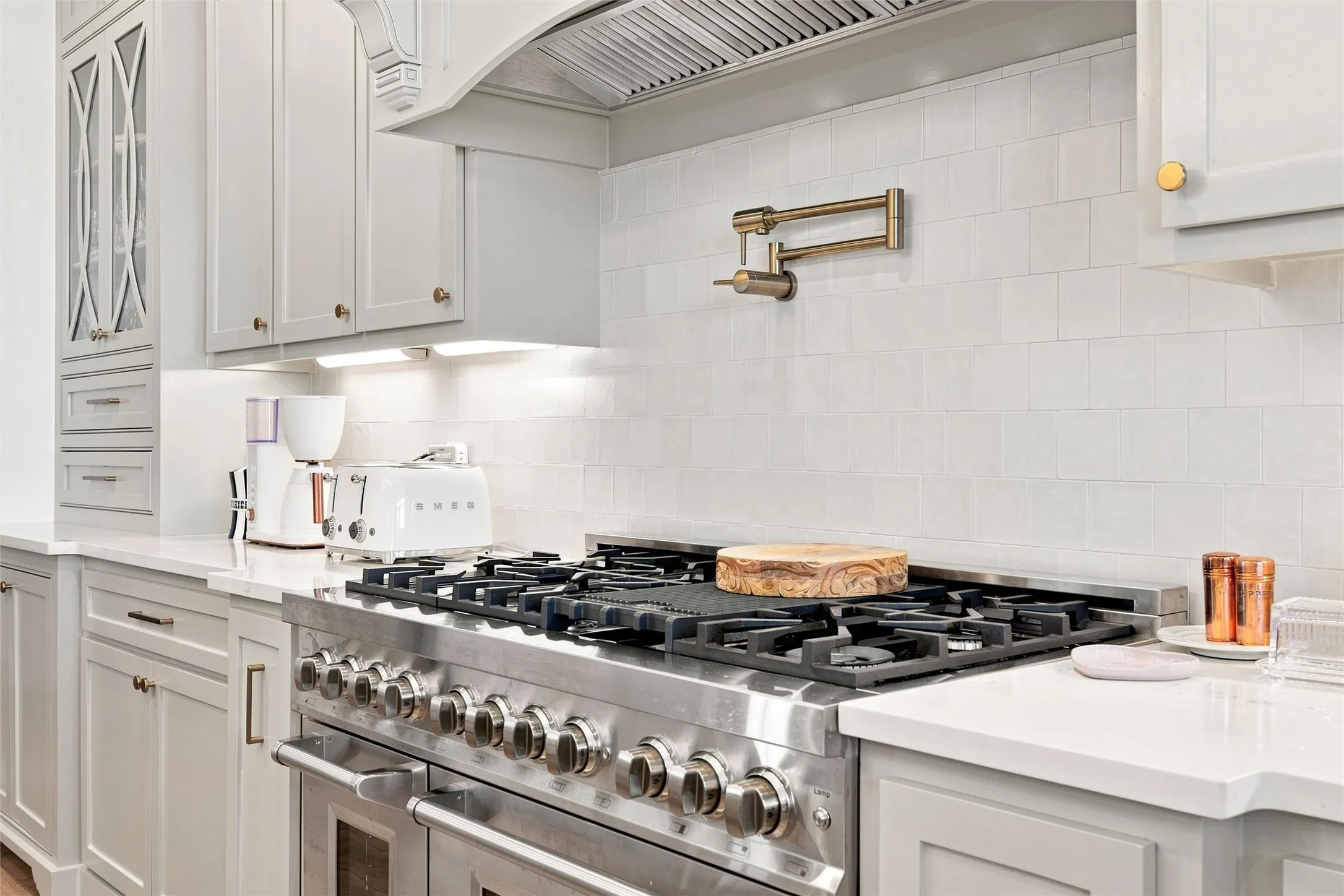 Professional-grade stainless steel range with a pot filler, set against a white subway tile backsplash