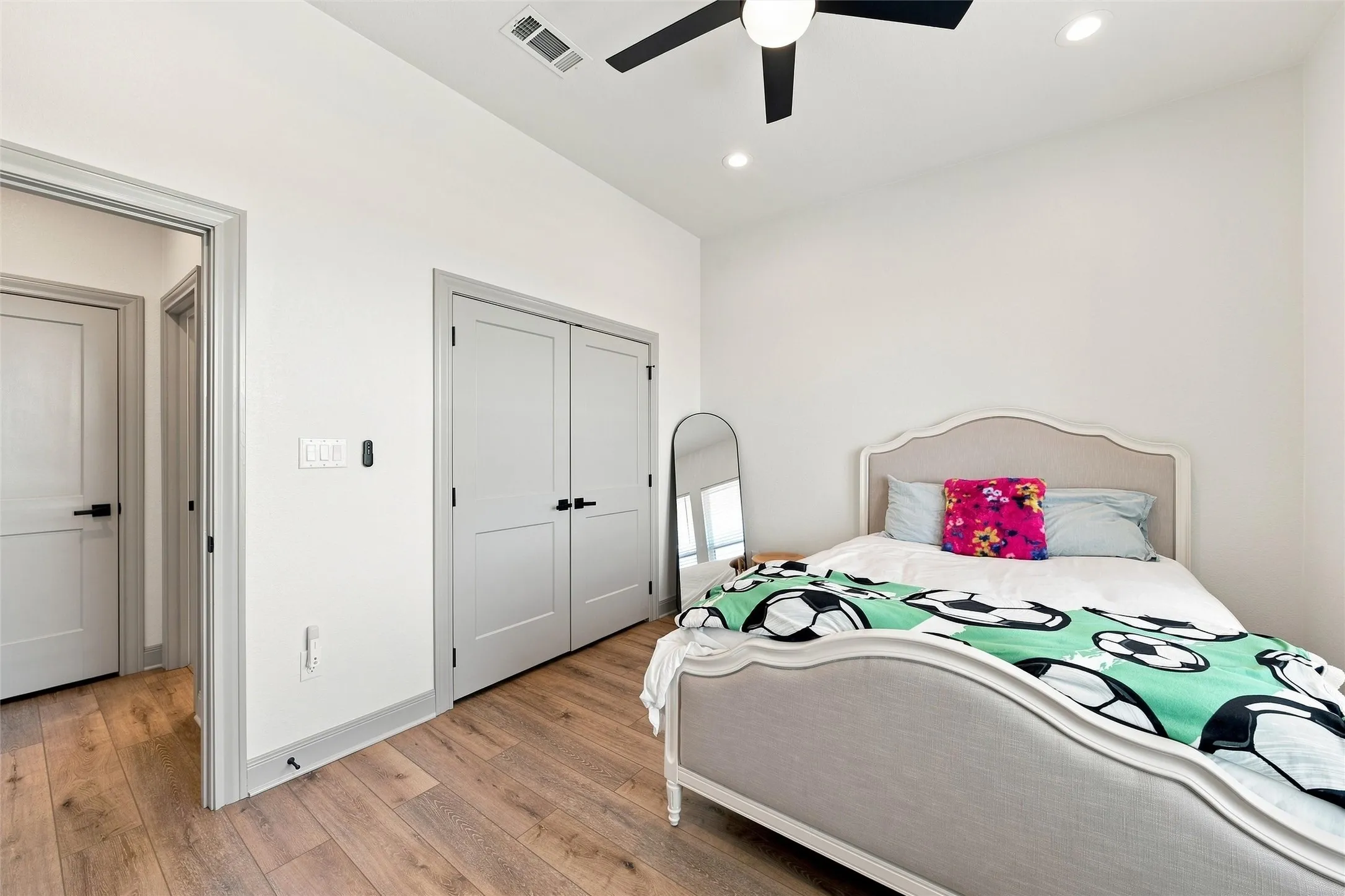 Light-filled room featuring wood-finish flooring, white walls, and a ceiling fan with integrated lighting