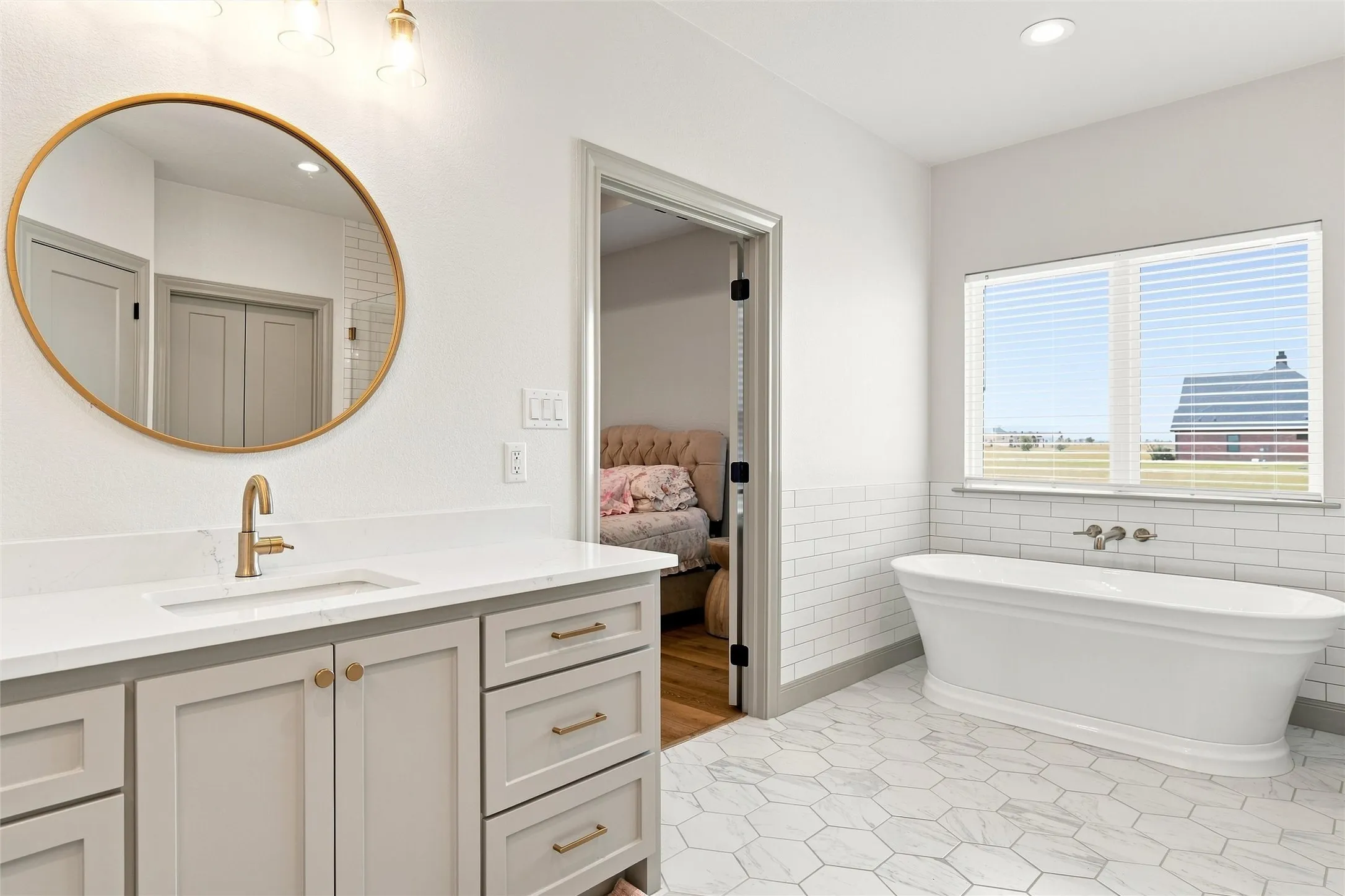 Bathroom with a freestanding soaking tub, white subway tile wainscoting, and large hexagonal floor tiles