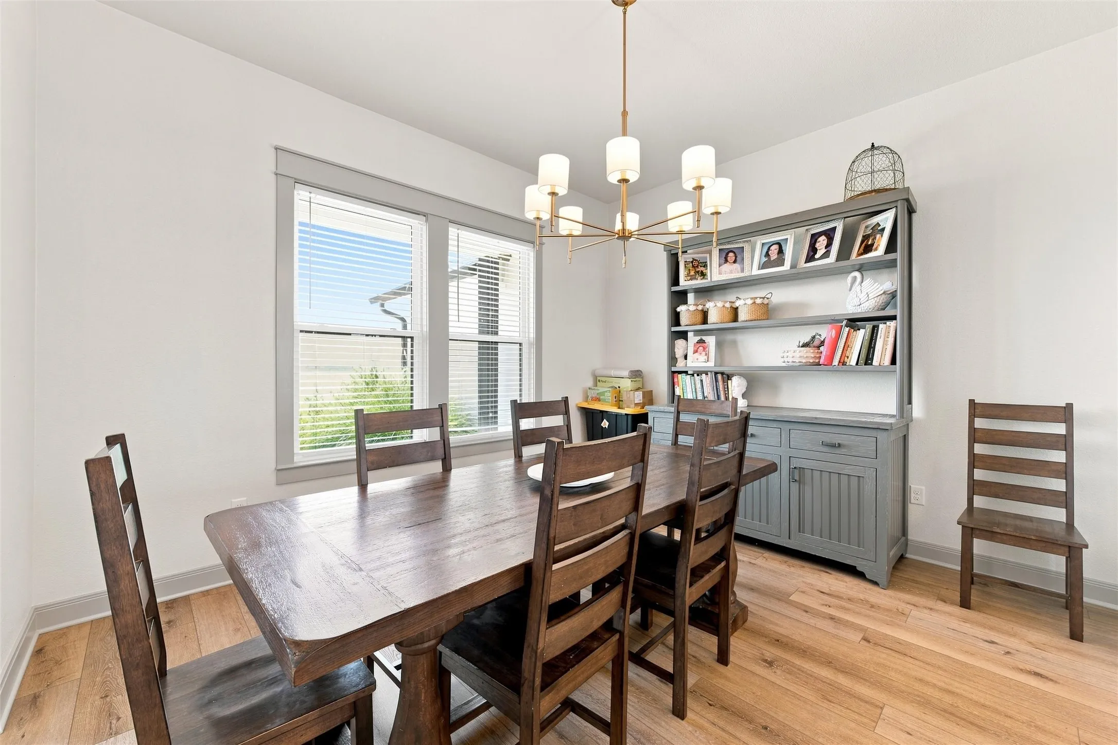 Dining area featuring wood-finish flooring, white walls, and a modern chandelier