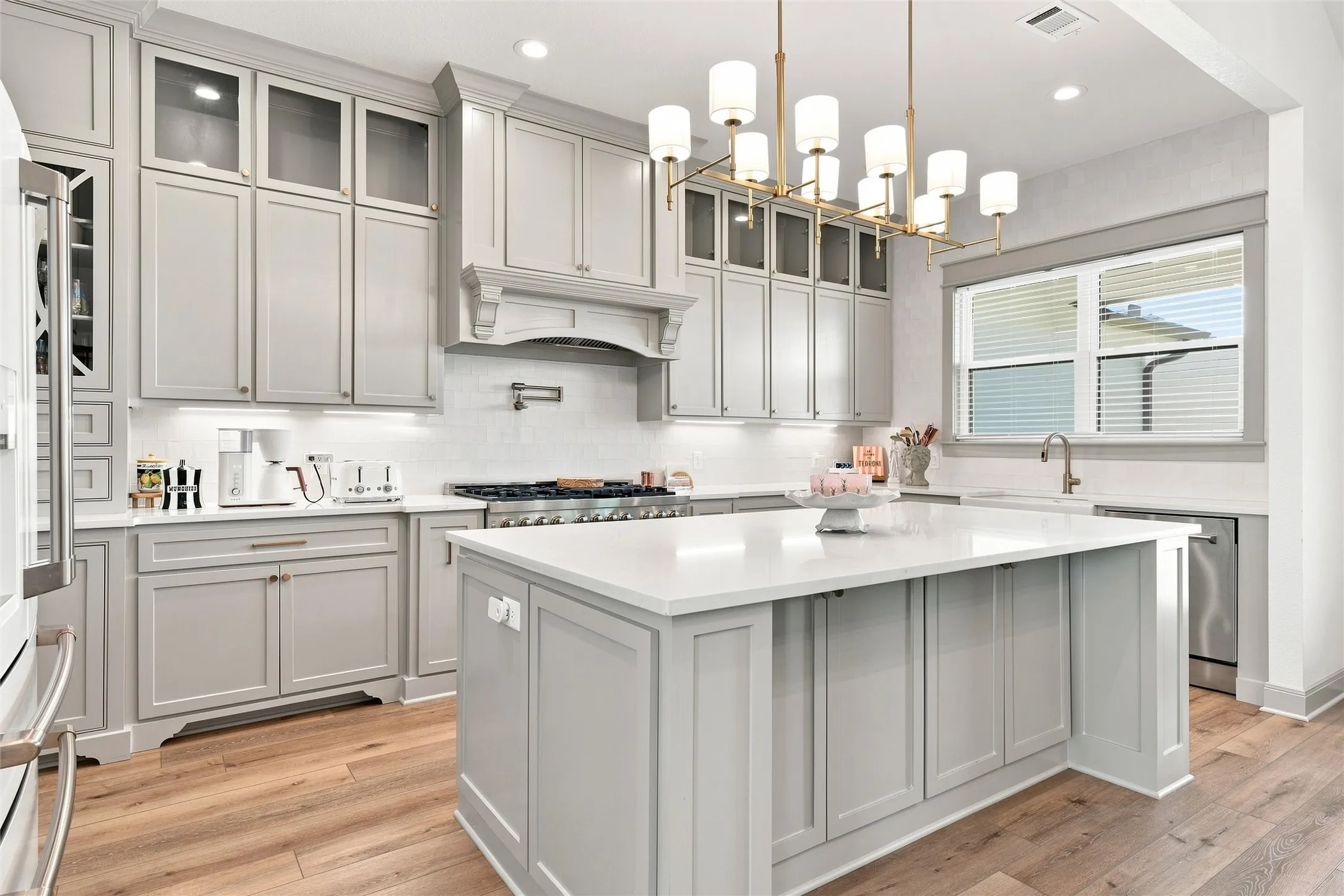 Gourmet kitchen with light gray cabinetry, a central island, and wood-finish flooring