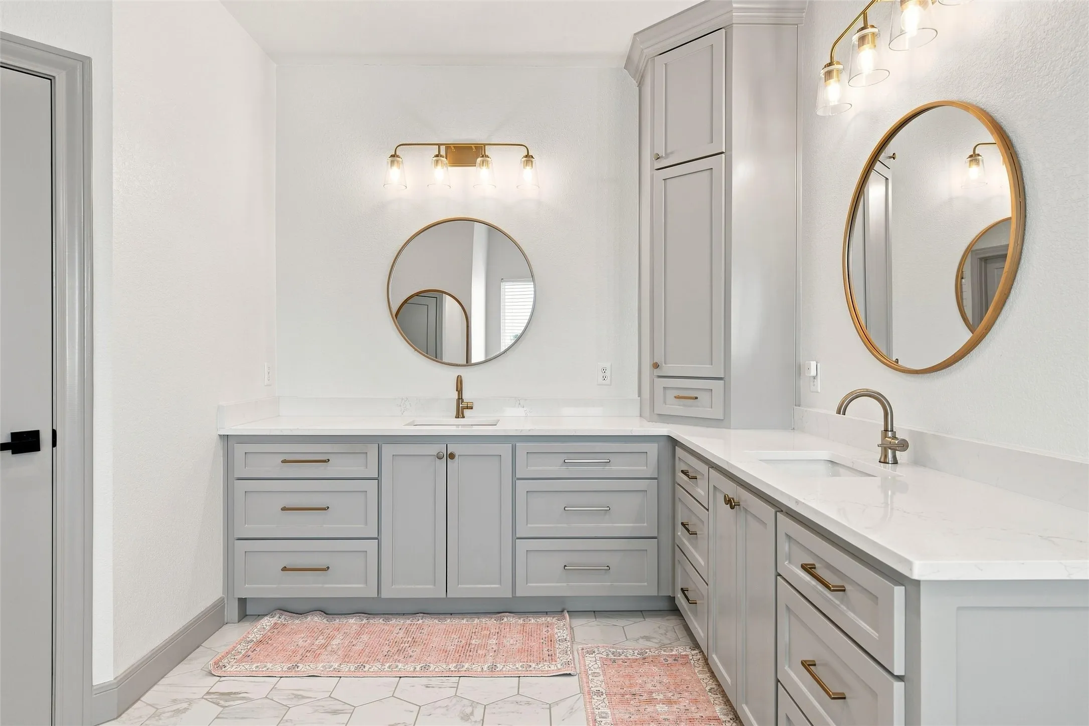Spacious bathroom featuring two vanity areas with light grey cabinetry and white countertops