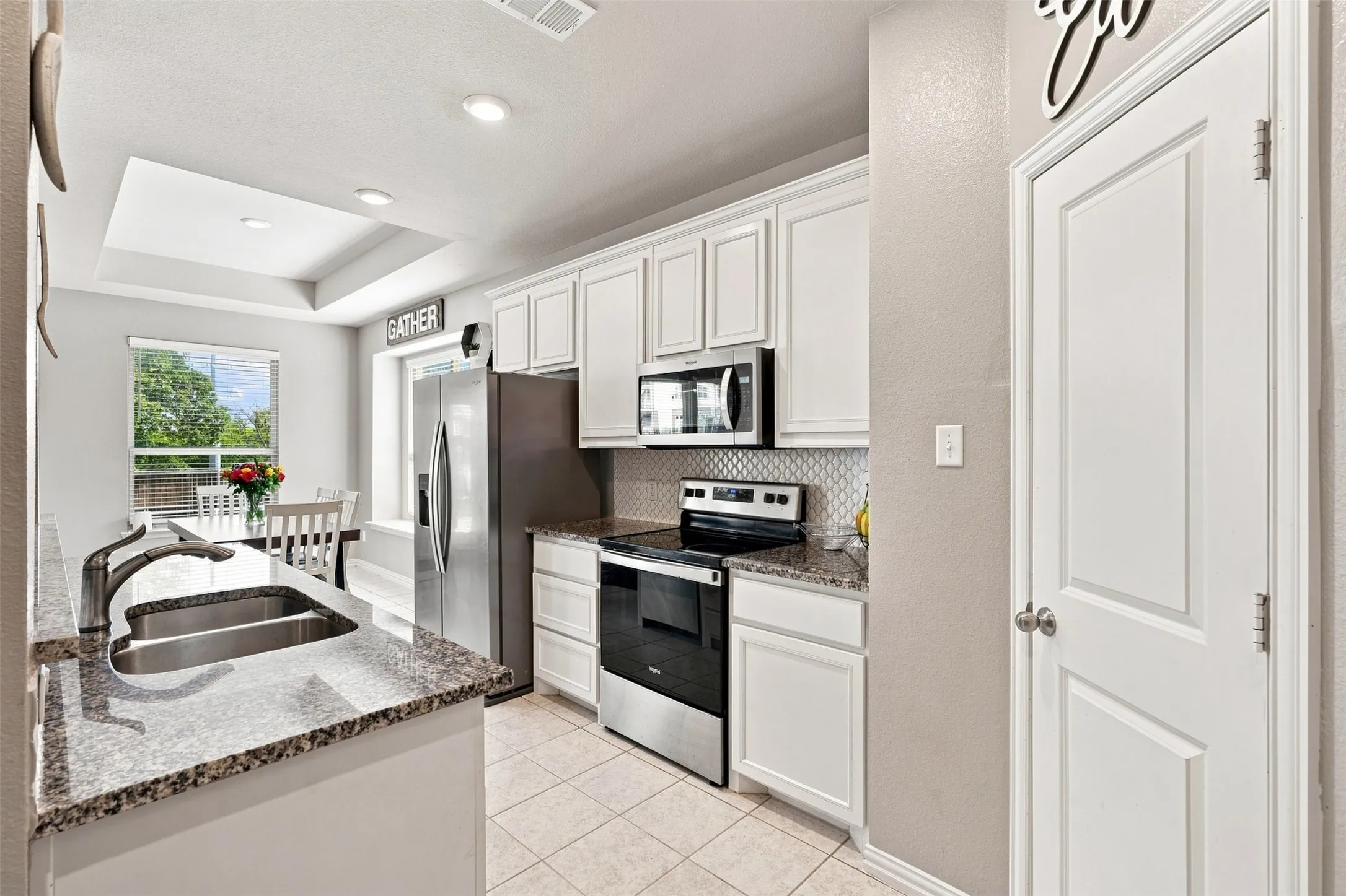 Kitchen featuring white cabinetry, stainless steel appliances, granite countertops, and a tiled backsplash