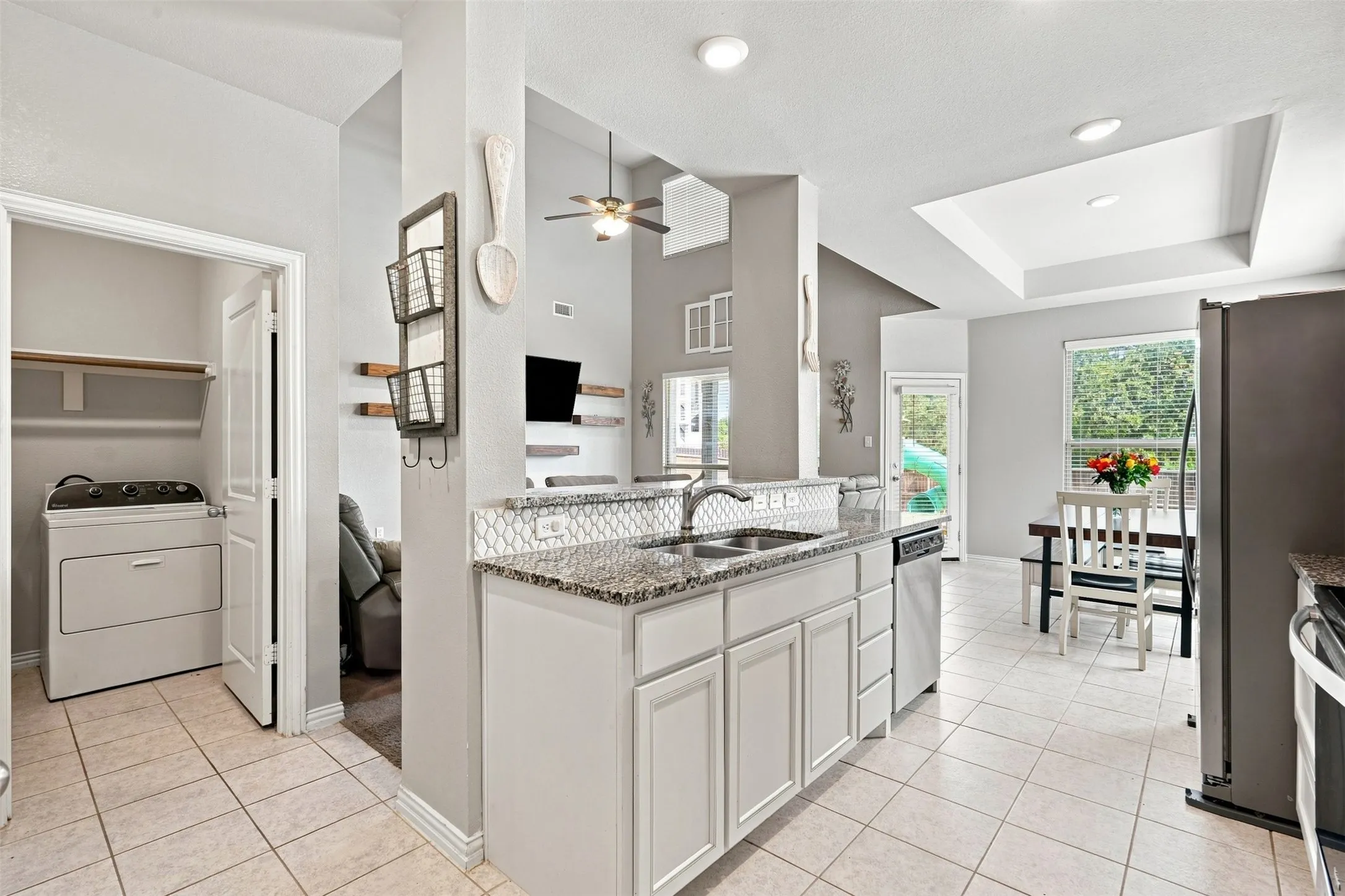 Kitchen featuring light gray cabinetry, granite countertops, and a white tile backsplash