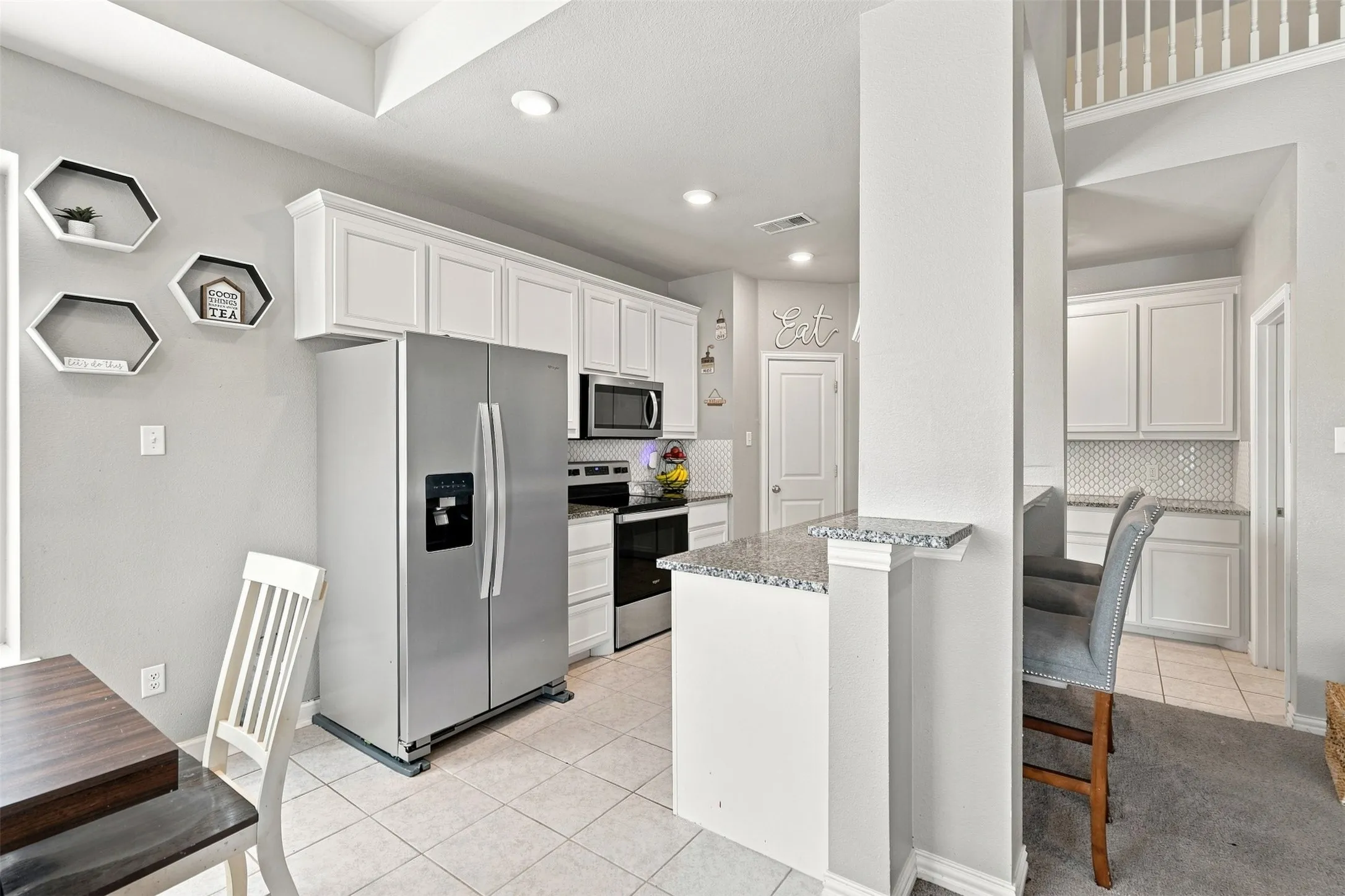 Kitchen featuring white cabinetry, stainless steel appliances, speckled countertops, and a subway tile backsplash