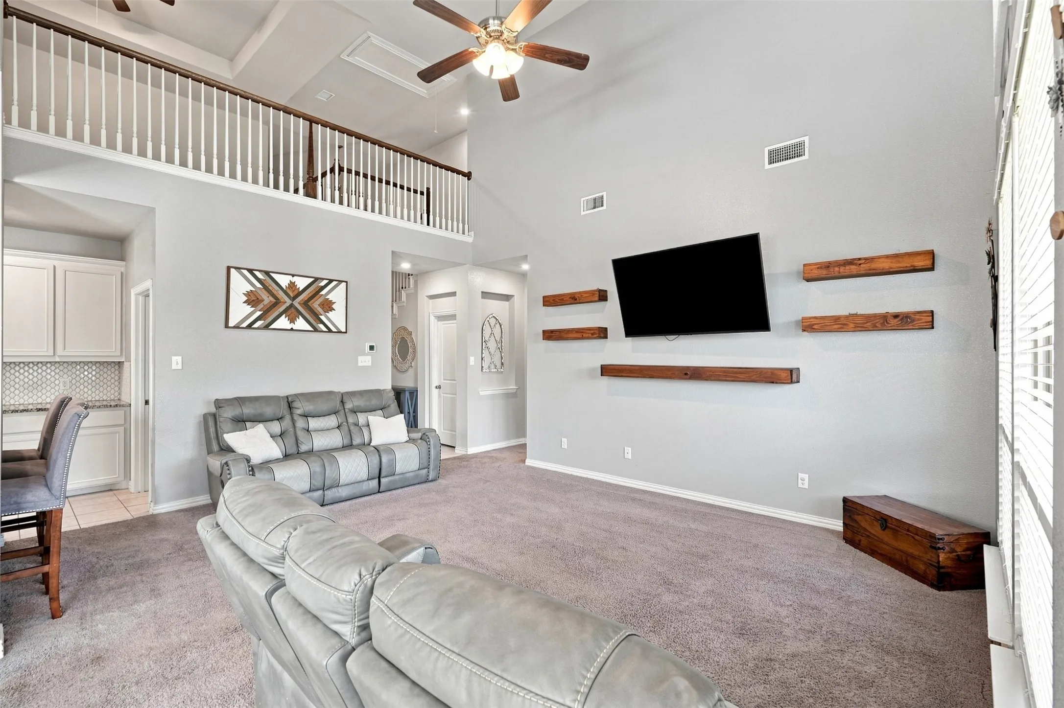 Living room featuring vaulted ceilings and a second-story interior balcony with white spindles and wood-finish railing