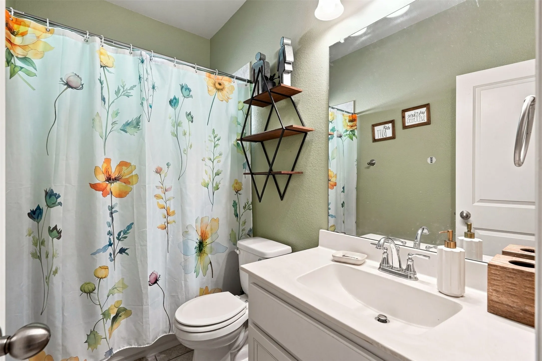 Bathroom featuring a white vanity with an integrated sink and chrome faucet, a large wall-mounted mirror, and a white toilet
