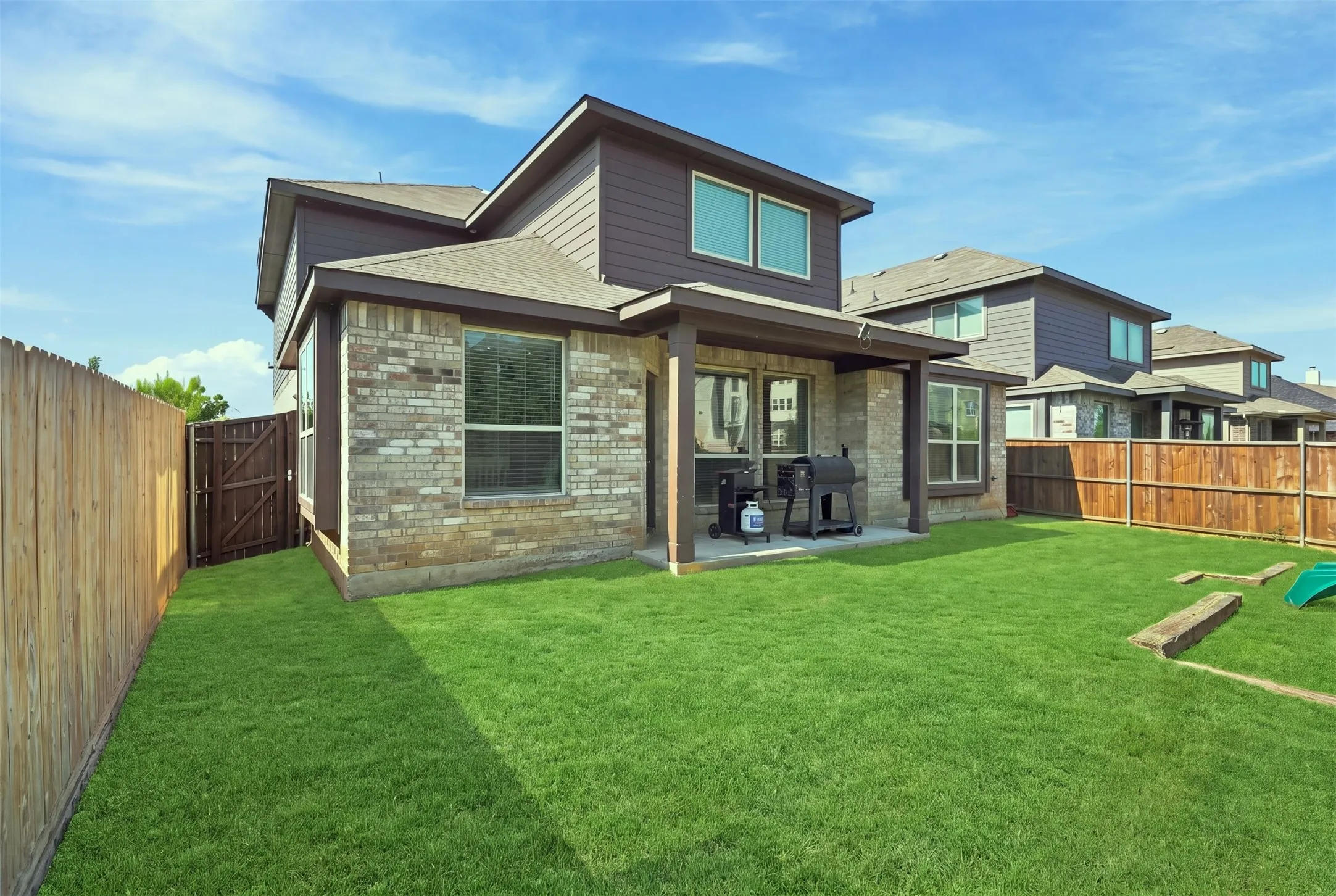 Spacious backyard with a covered patio, privacy fencing, and a side gate entry