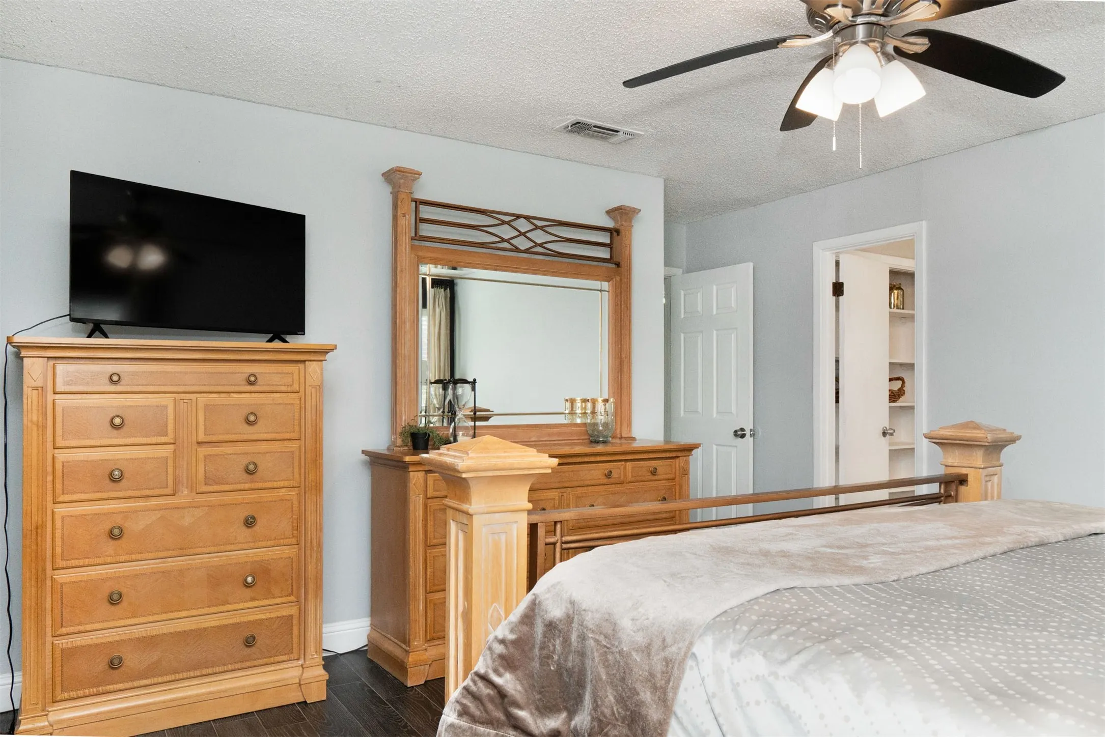 Spacious room featuring wood-finish flooring, a ceiling fan with integrated lighting, and light-toned wall paint