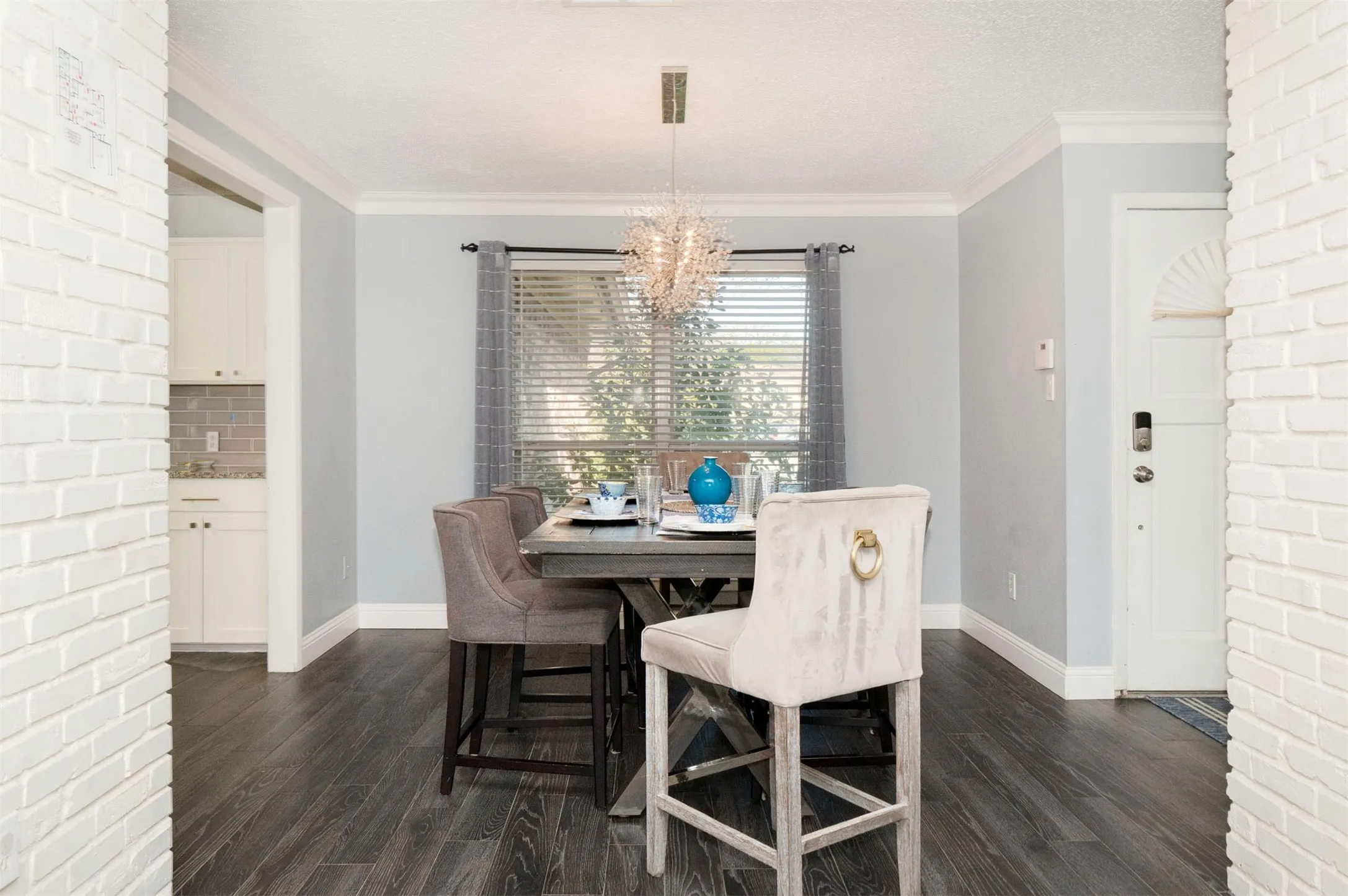 Dining area featuring dark wood-finish flooring, white crown molding, and a chandelier with a crystal-like design
