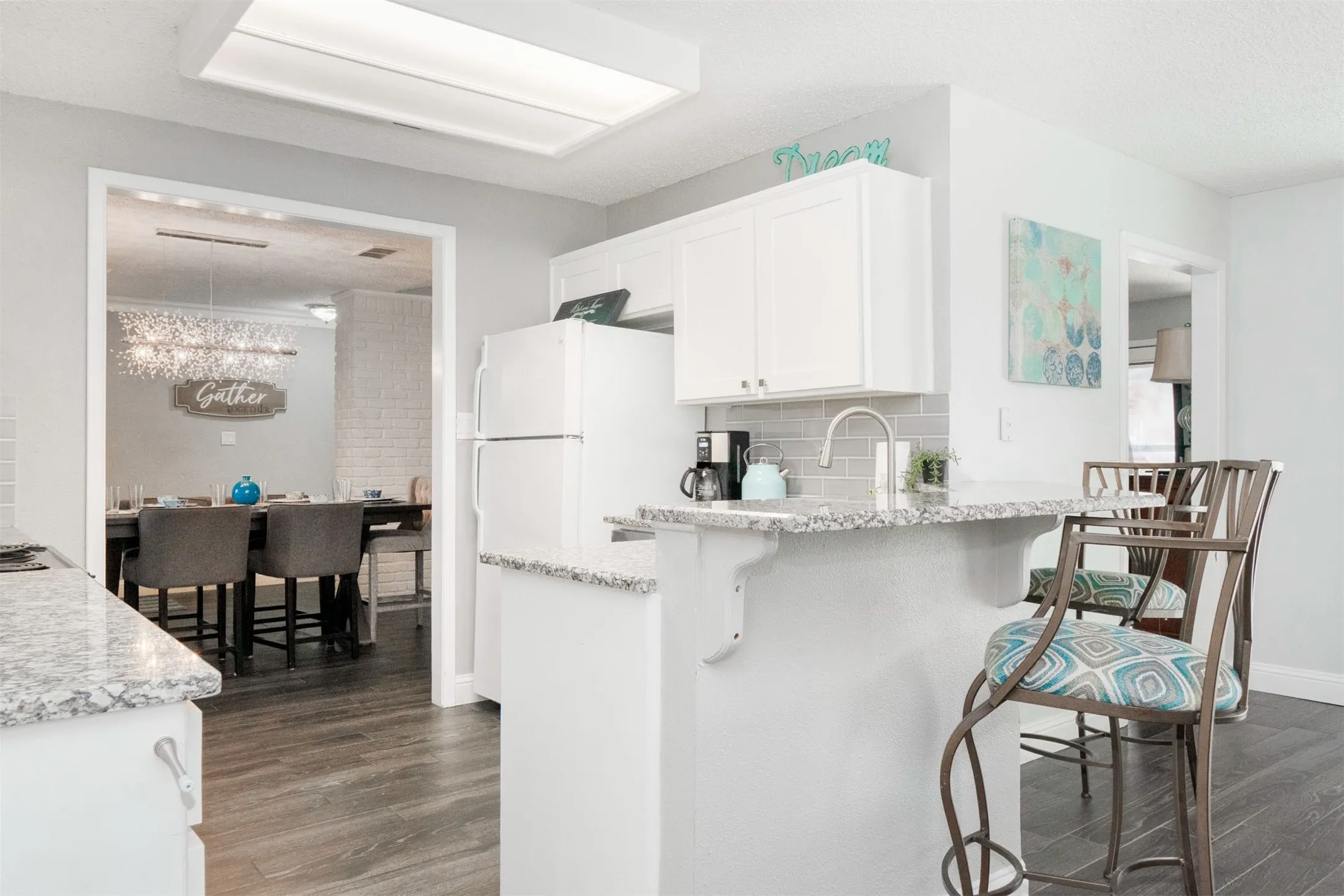 Kitchen featuring light-toned cabinetry, granite-style countertops, an undermount sink with a gooseneck faucet, and a subway tile backsplash