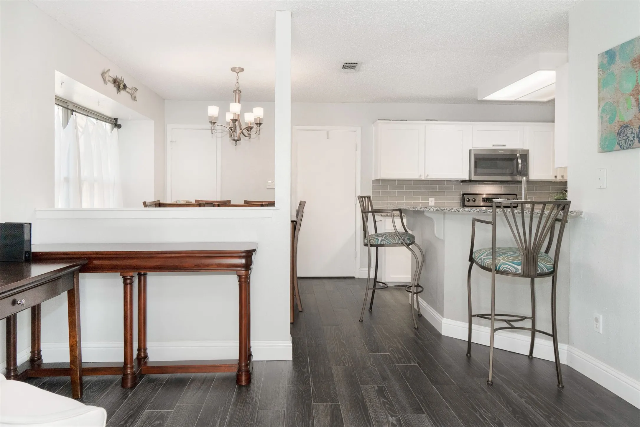 Kitchen with white cabinetry, stainless steel appliances, and a gray subway tile backsplash