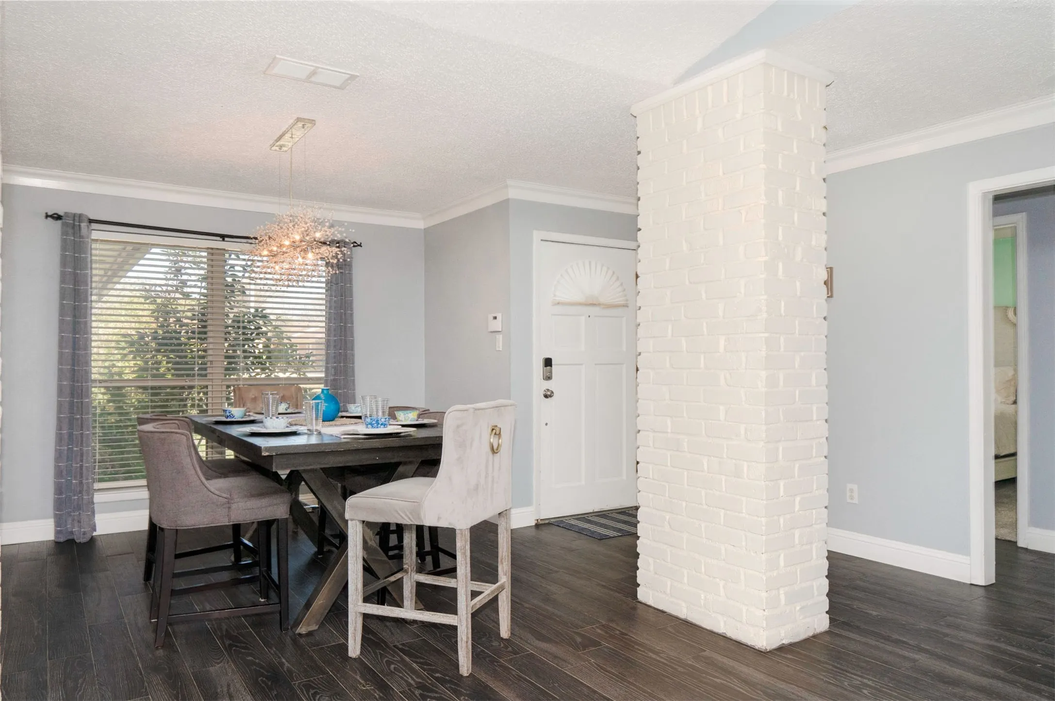 Dining area featuring dark wood-finish flooring, light grey wall tones, and a window with horizontal blinds