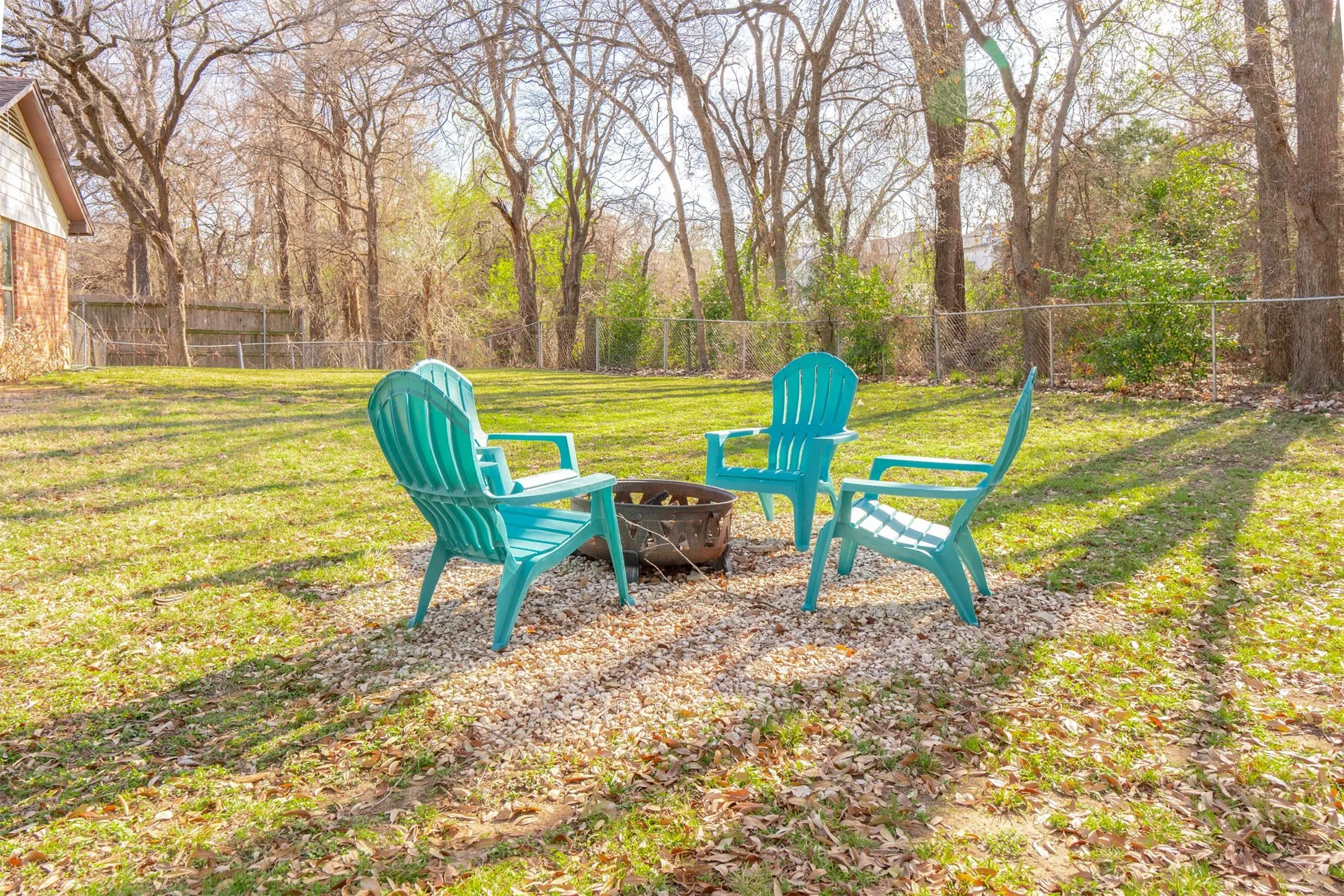 Expansive yard with green lawn, mature trees, and chain-link fencing