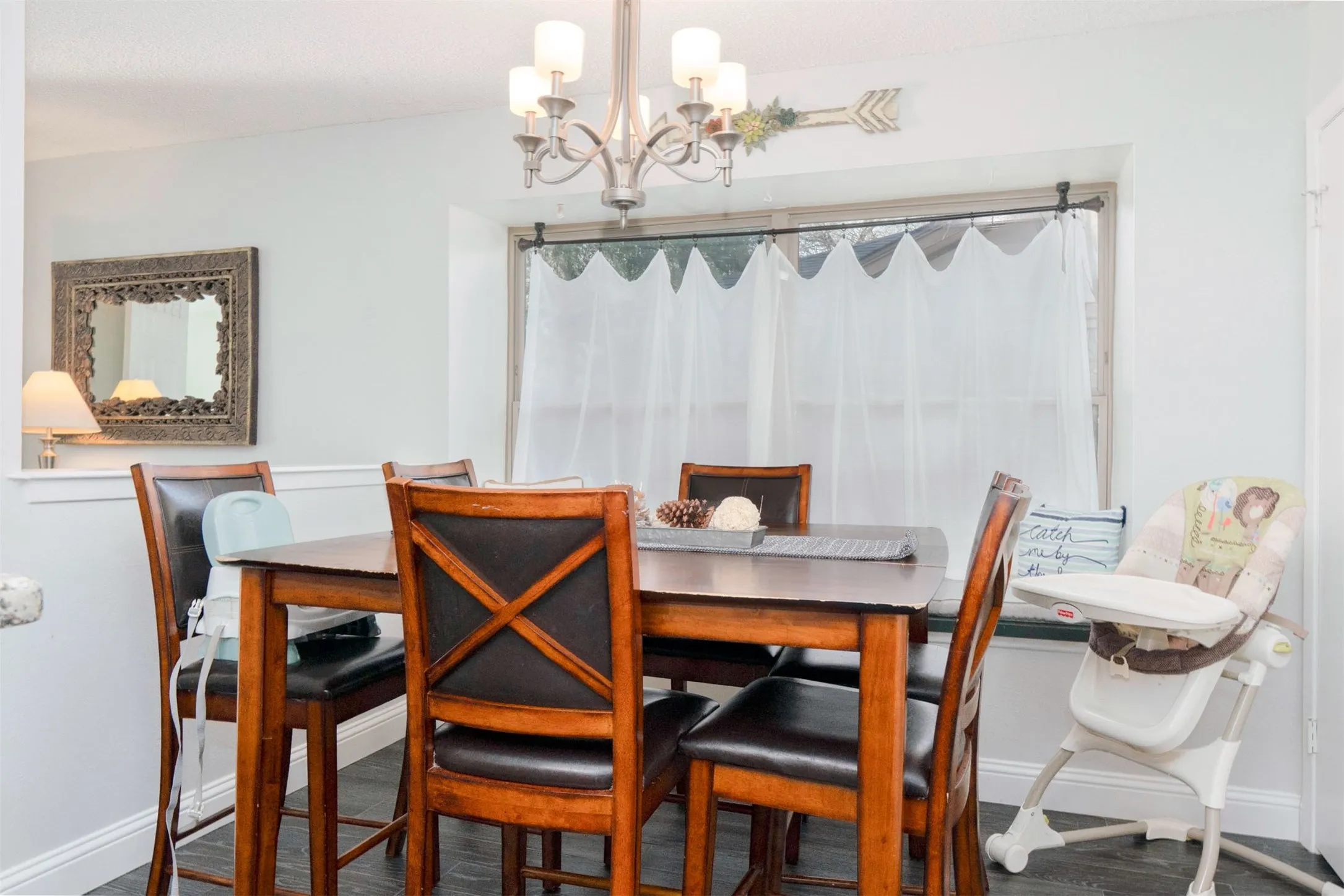 Dining area featuring wood-finish flooring, a contemporary chandelier, and a bay window with a built-in bench