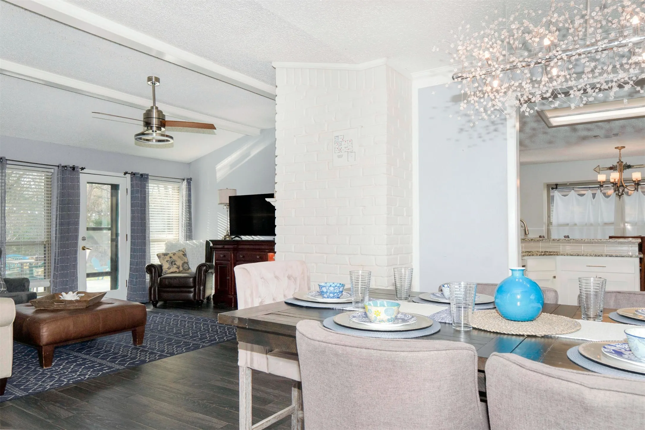 Dining area featuring a contemporary chandelier, wood-finish flooring, and a white brick architectural element