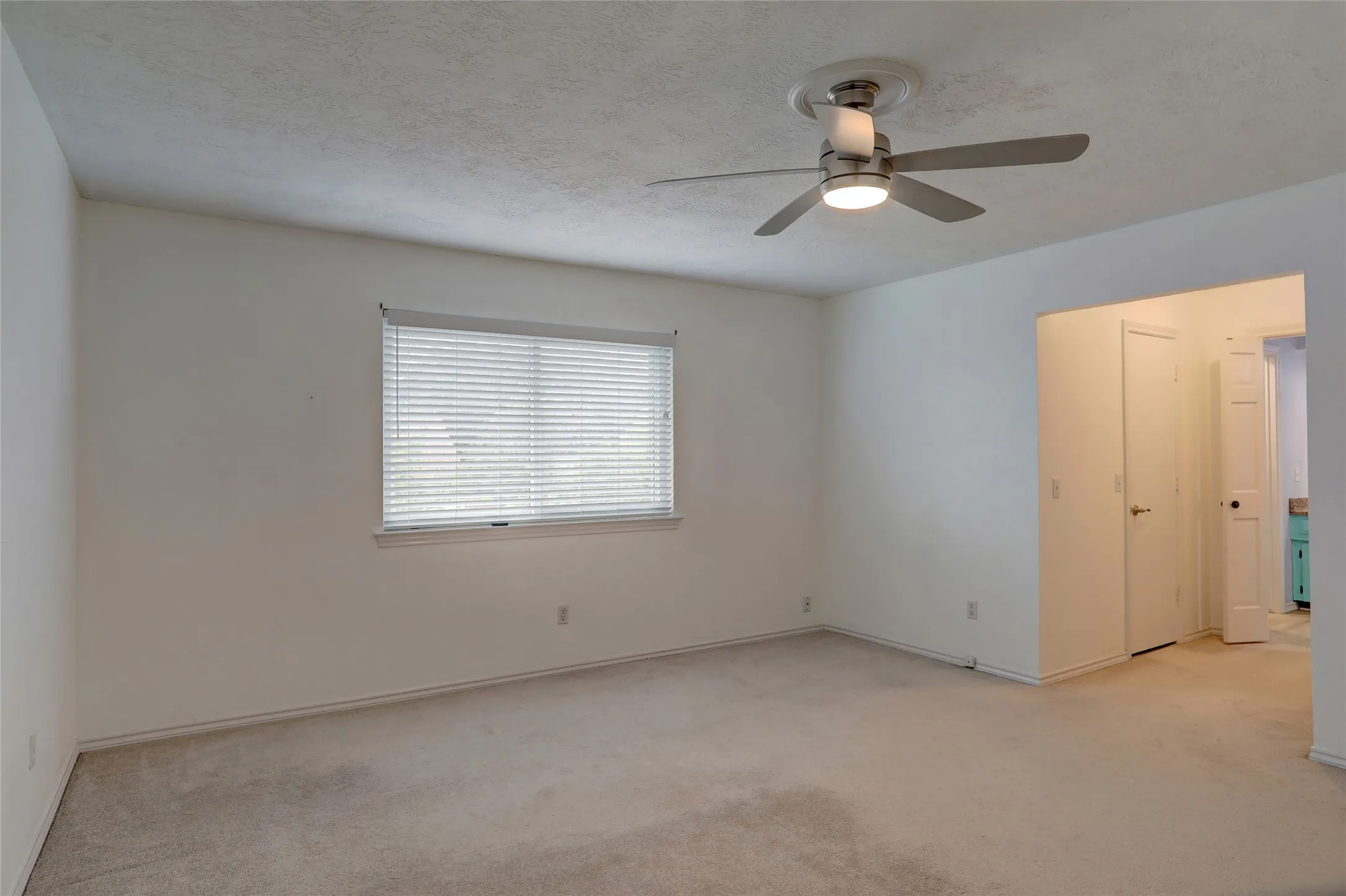 Bright room featuring a window with horizontal blinds, carpet flooring, and a ceiling fan with integrated lighting