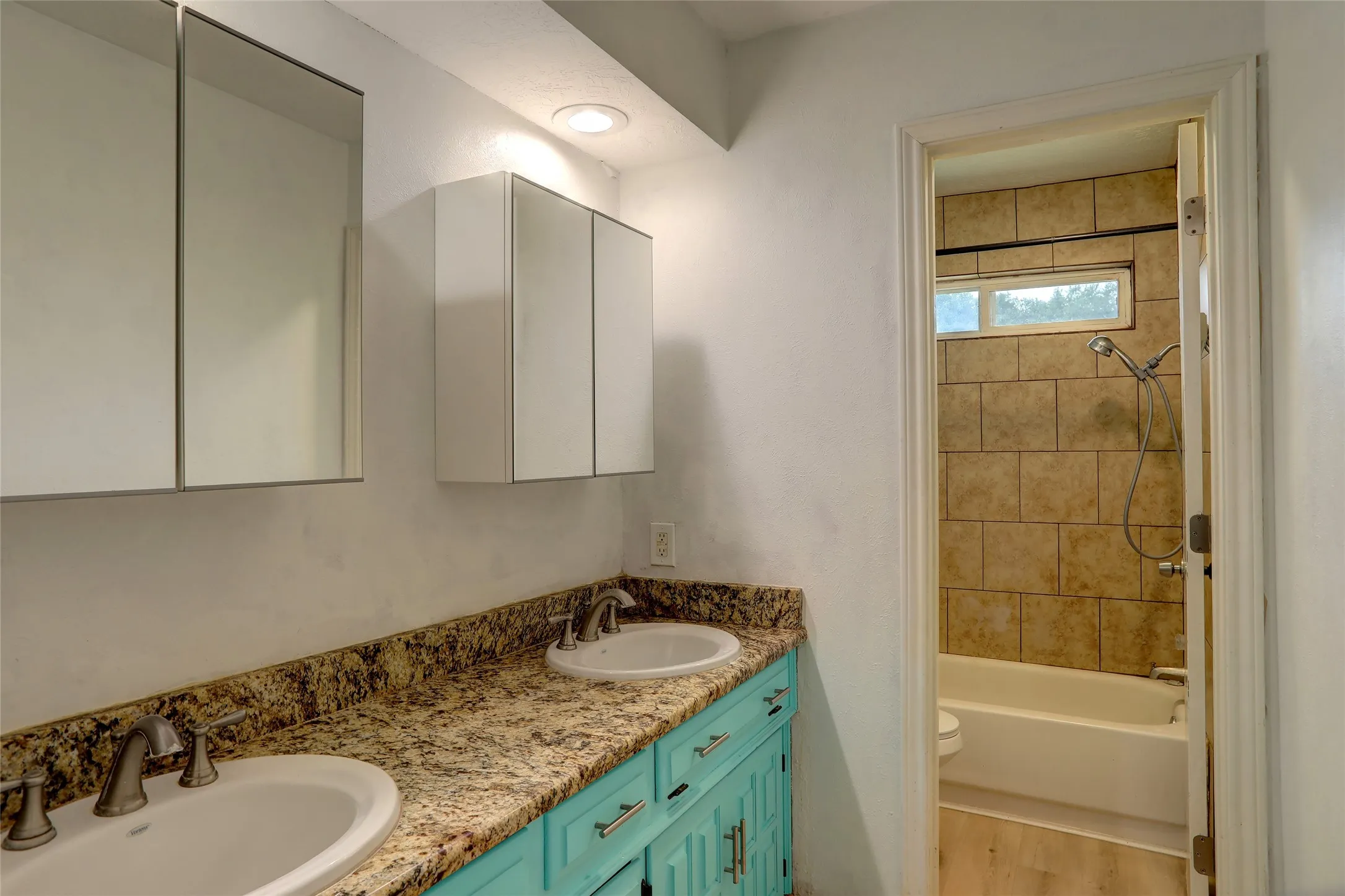 Bathroom featuring a dual vanity with a granite-style countertop, two undermount sinks, and a turquoise-painted cabinet base