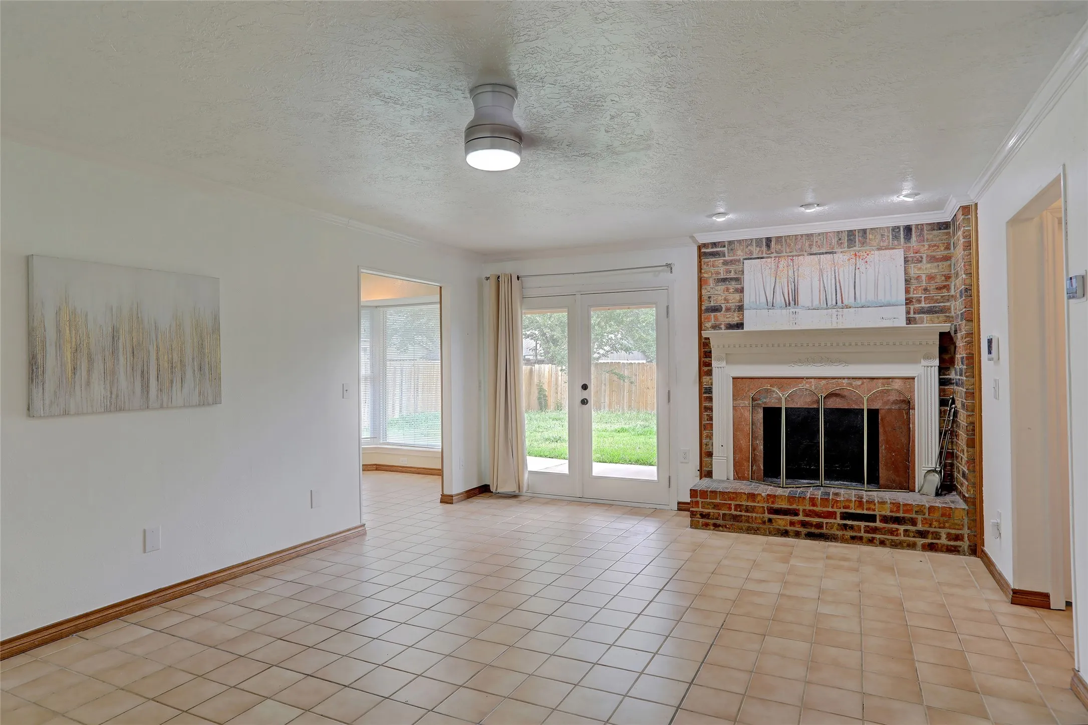Spacious living area featuring a brick fireplace with a detailed mantel, recessed lighting, and tile flooring