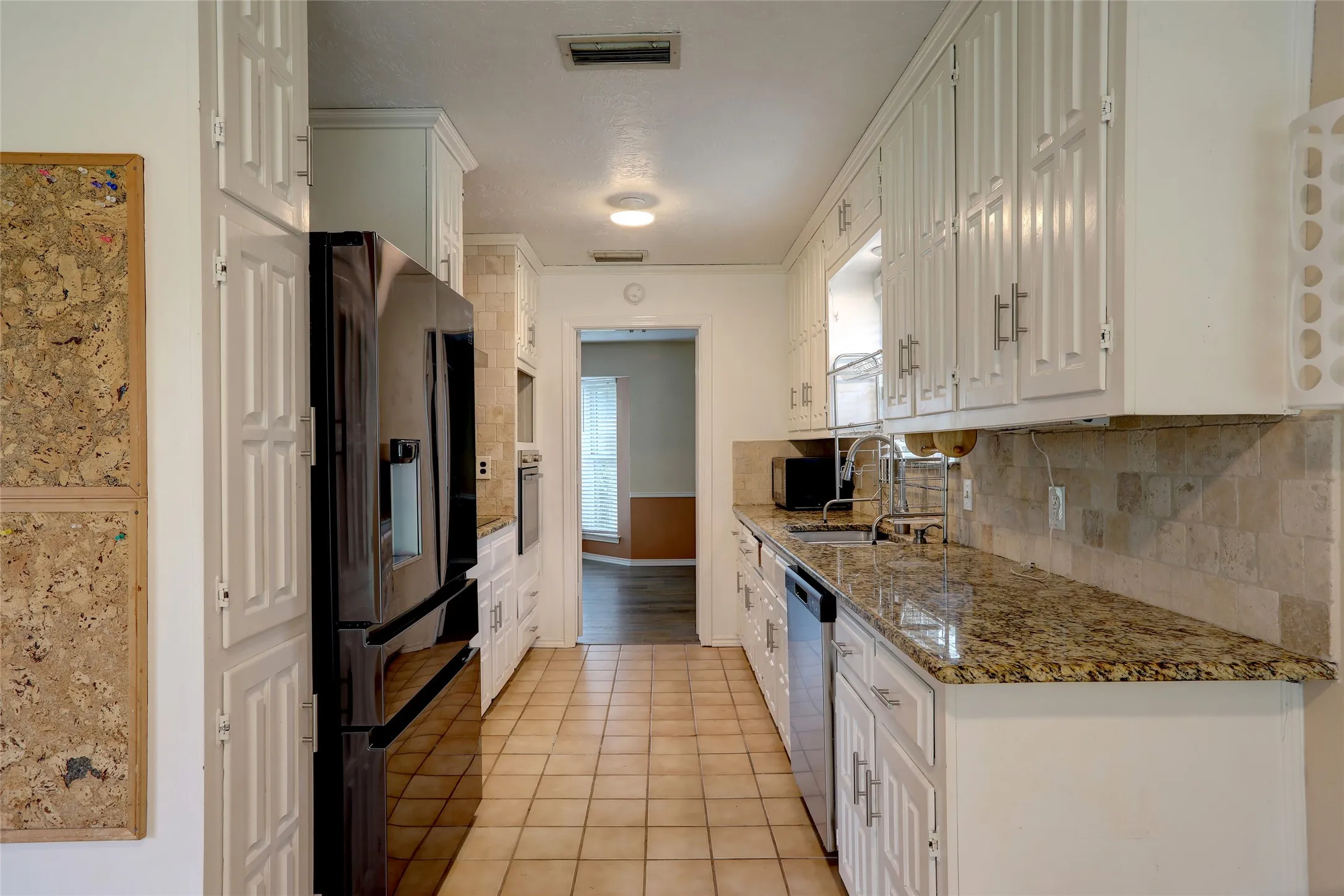 Galley kitchen featuring white cabinetry, granite countertops, and a tiled backsplash